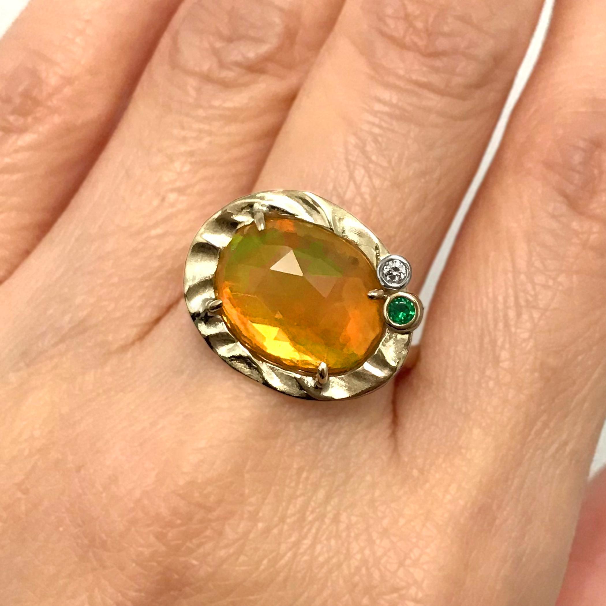 K.Mita's contemporary Dreamy Dawn Ring, which is handmade from 14 Karat Yellow Gold, features a 2.42 Carat Ethiopian Opal (16mm at its widest) accented with a 0.02 Carat Diamond and a 0.045 Carat Green Garnet. The shank is only 2.3mm wide. Ring Size