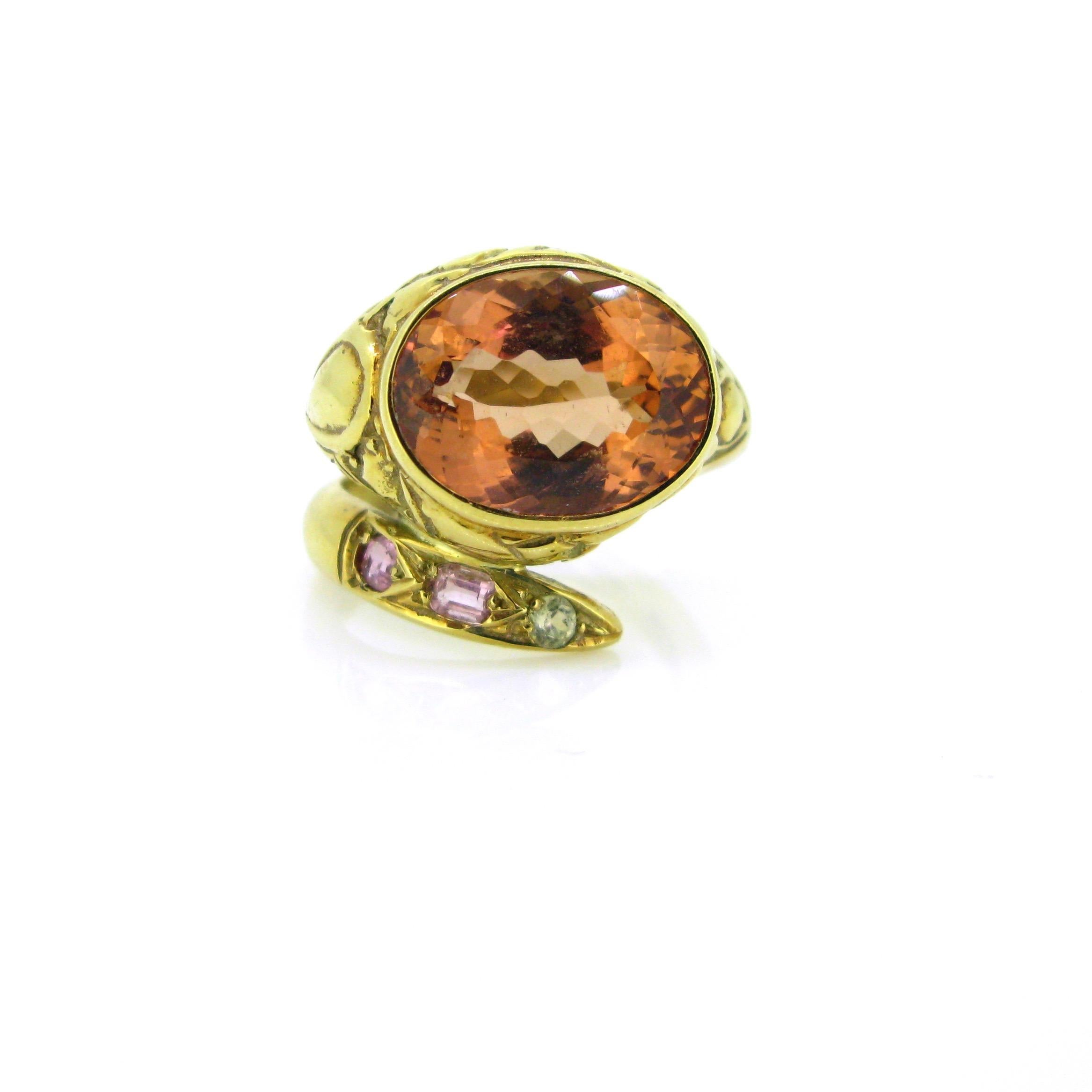 This ring represents a snake. His head is adorned with a stunning orange pinkish topaz weighing around 9.50ct. His tail is set with 3 naturals stones : 2 of them are pinks with naturals inclusions and the last one has a light green color. They might