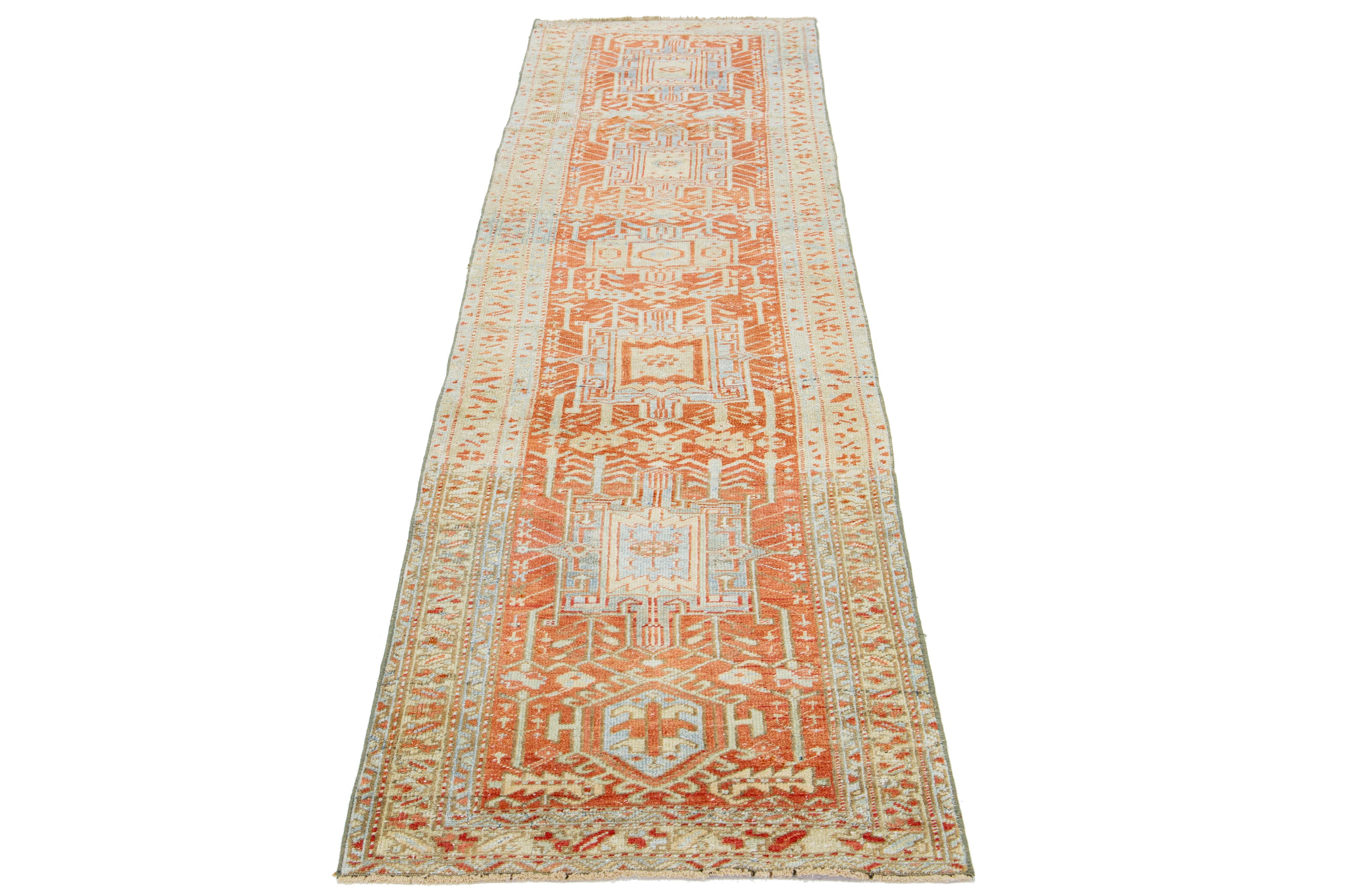 This beautiful Heriz hand-knotted wool runner from the 20th century features an orange rust field. The piece showcases stunning blue, tan, and brown accents in an exquisite tribal geometric design.

This rug measures 2'8