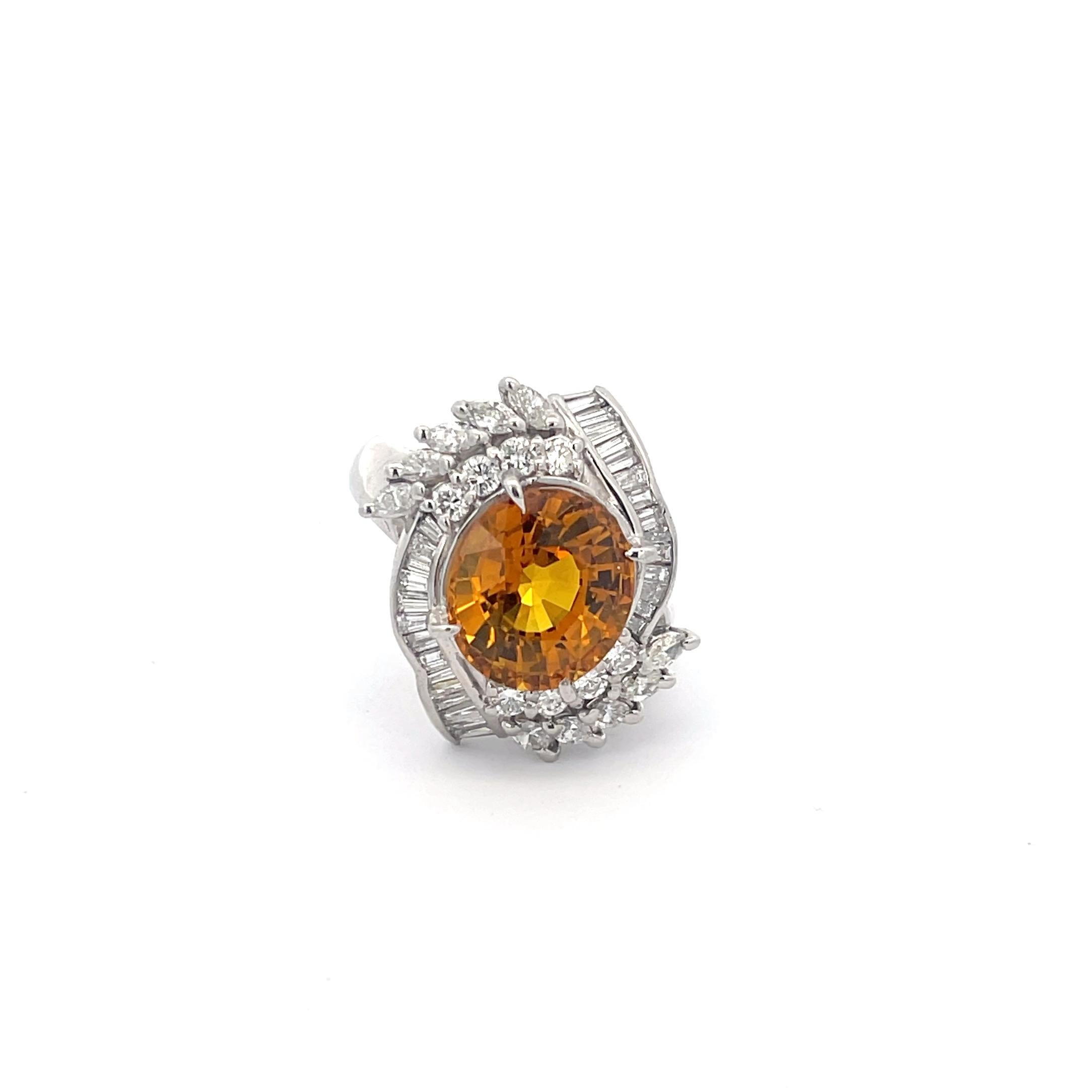 Orange Sapphire and Diamond Ring in Platinum. The ring features an oval cut 6.46ct sapphire accentuated with 1.16ctw of round, marquise, and baguette cut diamonds. Ring size 6.75 and weighs 12.6 grams.