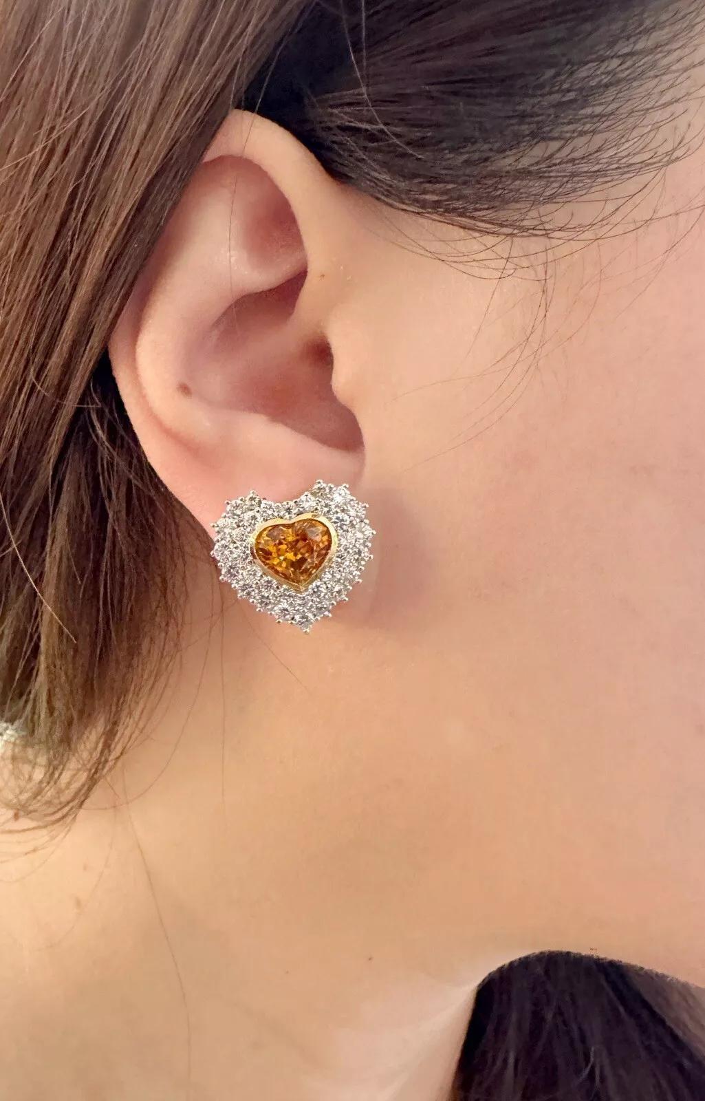 Boucles d'oreilles cœur en saphir et diamant en or jaune et or blanc 18k

Les boucles d'oreilles en saphir et diamant présentent des saphirs orange en forme de cœur sertis sur un chaton en or jaune 18 carats, entourés de deux rangées de diamants