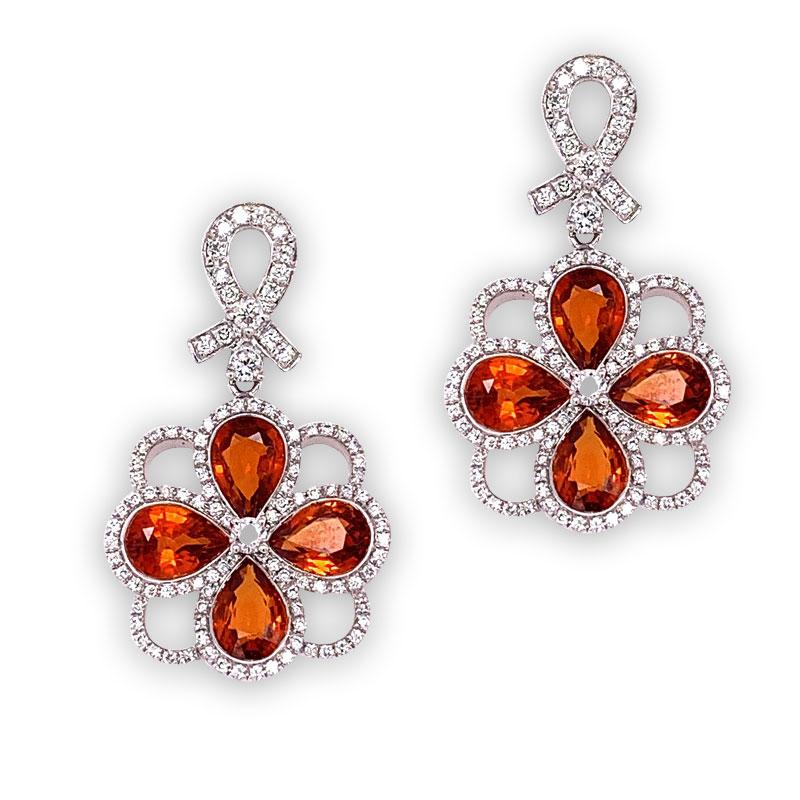 Gem studded drop earrings! This lovely set features 7.14 carats of pear shaped orange sapphire perfectly matching in size, shape and color. They are accented by 0.92 carats of round cut diamonds set around and above the sapphires. Made in 18k white