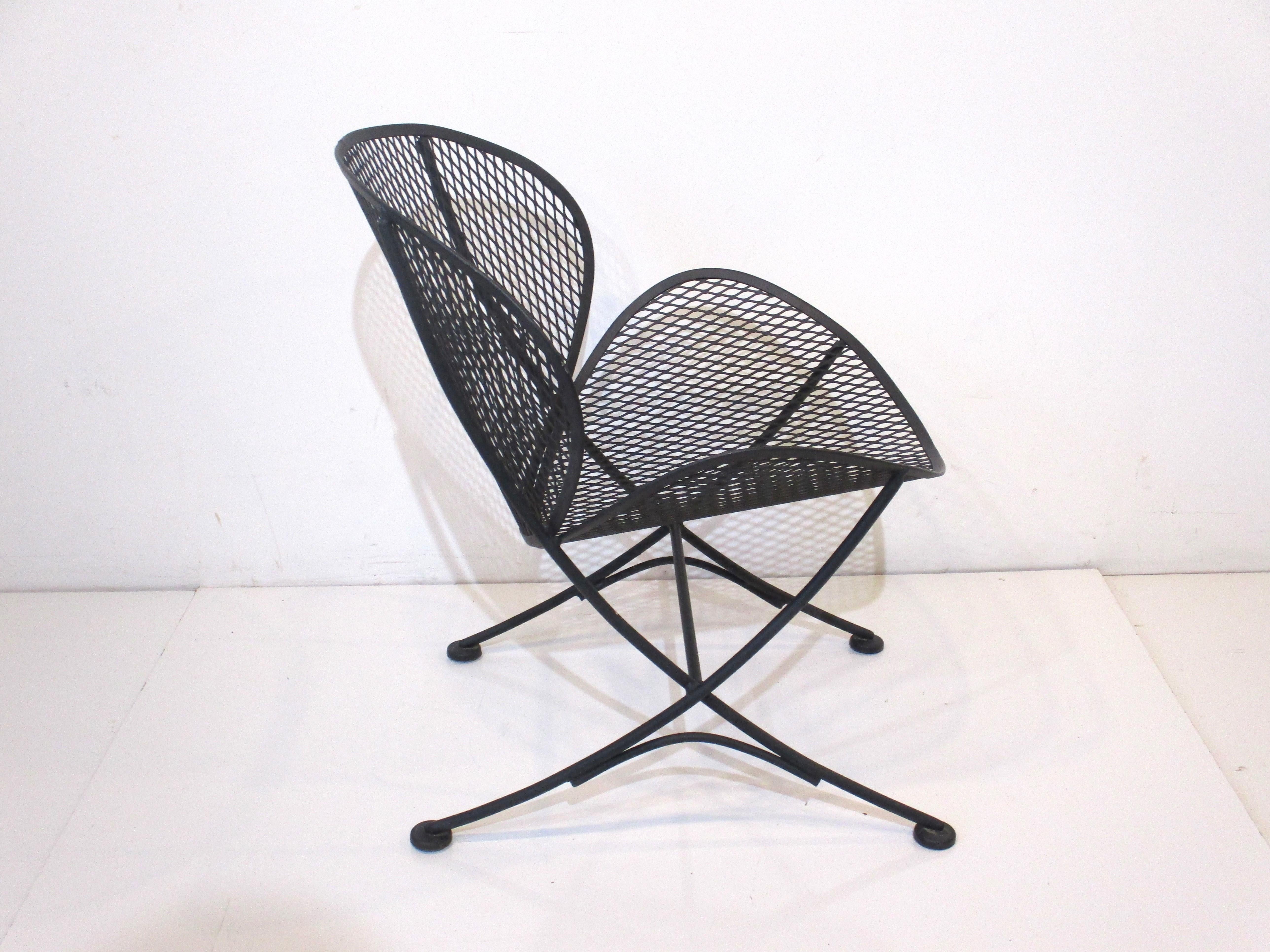 A satin black metal framed indoor or outdoor lounge chair with metal mesh seat sculpturally formed like a orange slice hence the name . The curved legs sit on pads to provide support , manufactured by John Salterini Italy and designed by Maurizio