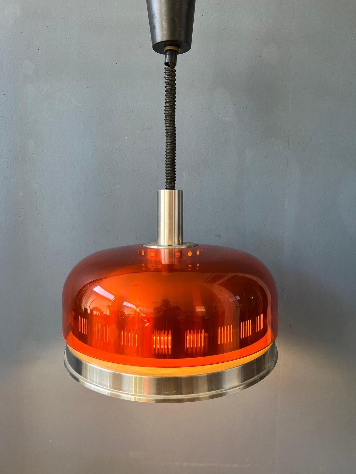 Very unique orange space age UFO pendant lamp. The light has a transparent, orange outer shade and aluminium inner shade. The light escapes beautifully through patterned aluminium. One of a kind! The lamp requires one E27 (standard)