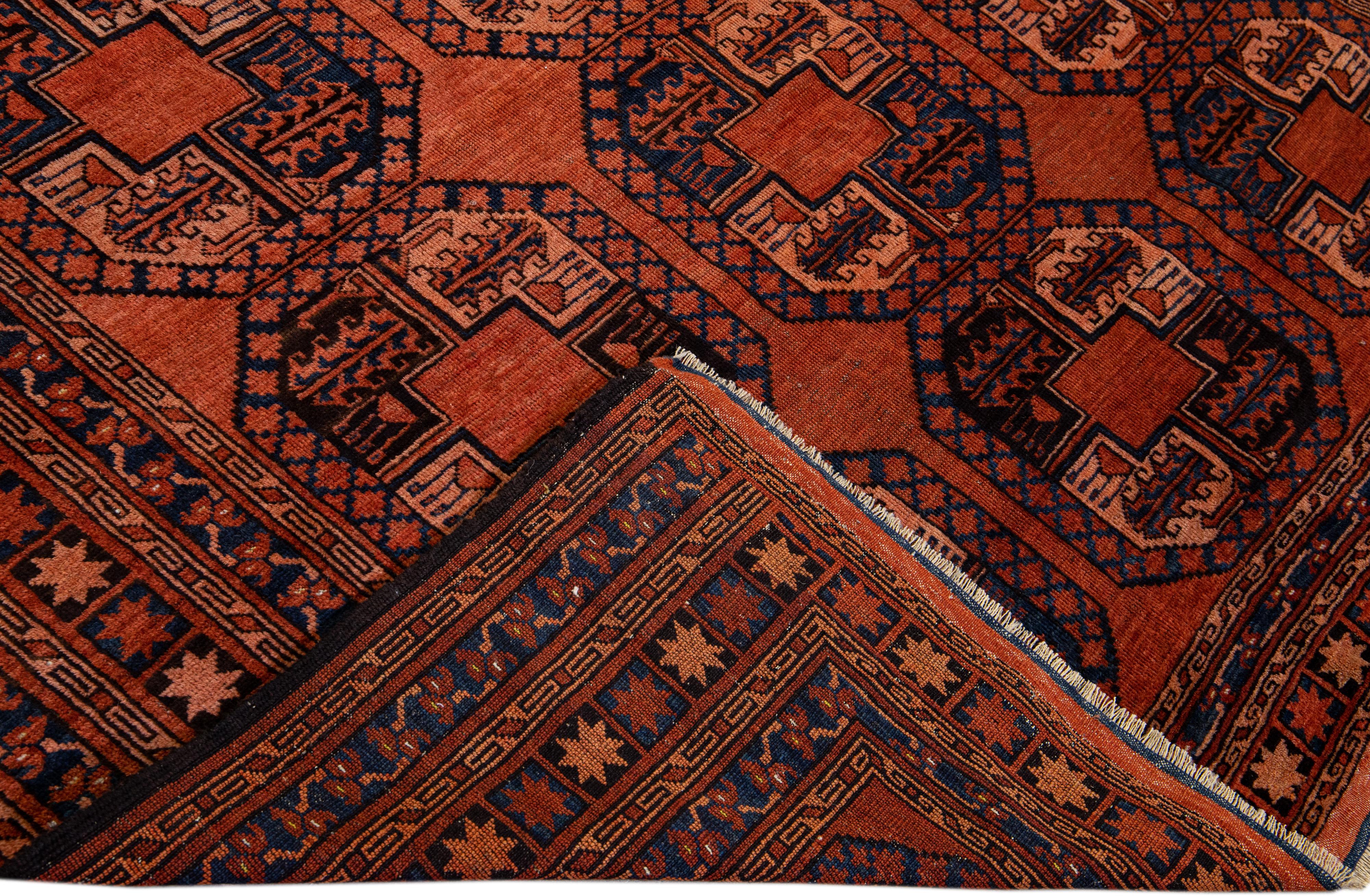 Beautiful vintage Turkmen hand-knotted wool rug with an orange field. This Persian rug has navy blue accents in a gorgeous all-over geometric Pattern Design.

This rug measures: 6'9