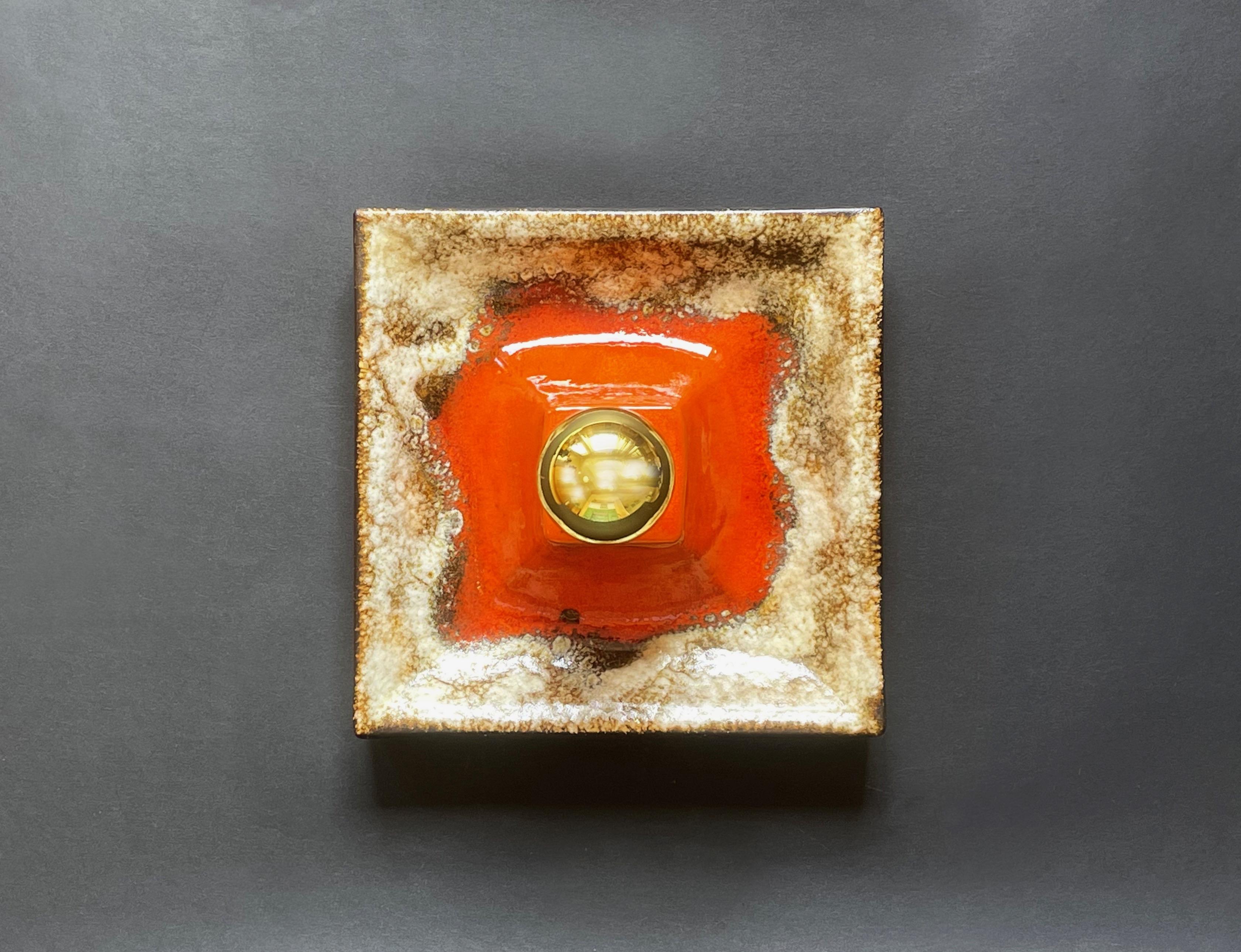 Aplique futurista en el emblemático estilo alemán Fat Lava de Hustadt Leuchten, obra de cerámica probablemente de Pan Keramik.
Un divertido diseño de un cono volcánico cuadrado en naranja brillante, en erupción en tonos beige y marrón claro, con