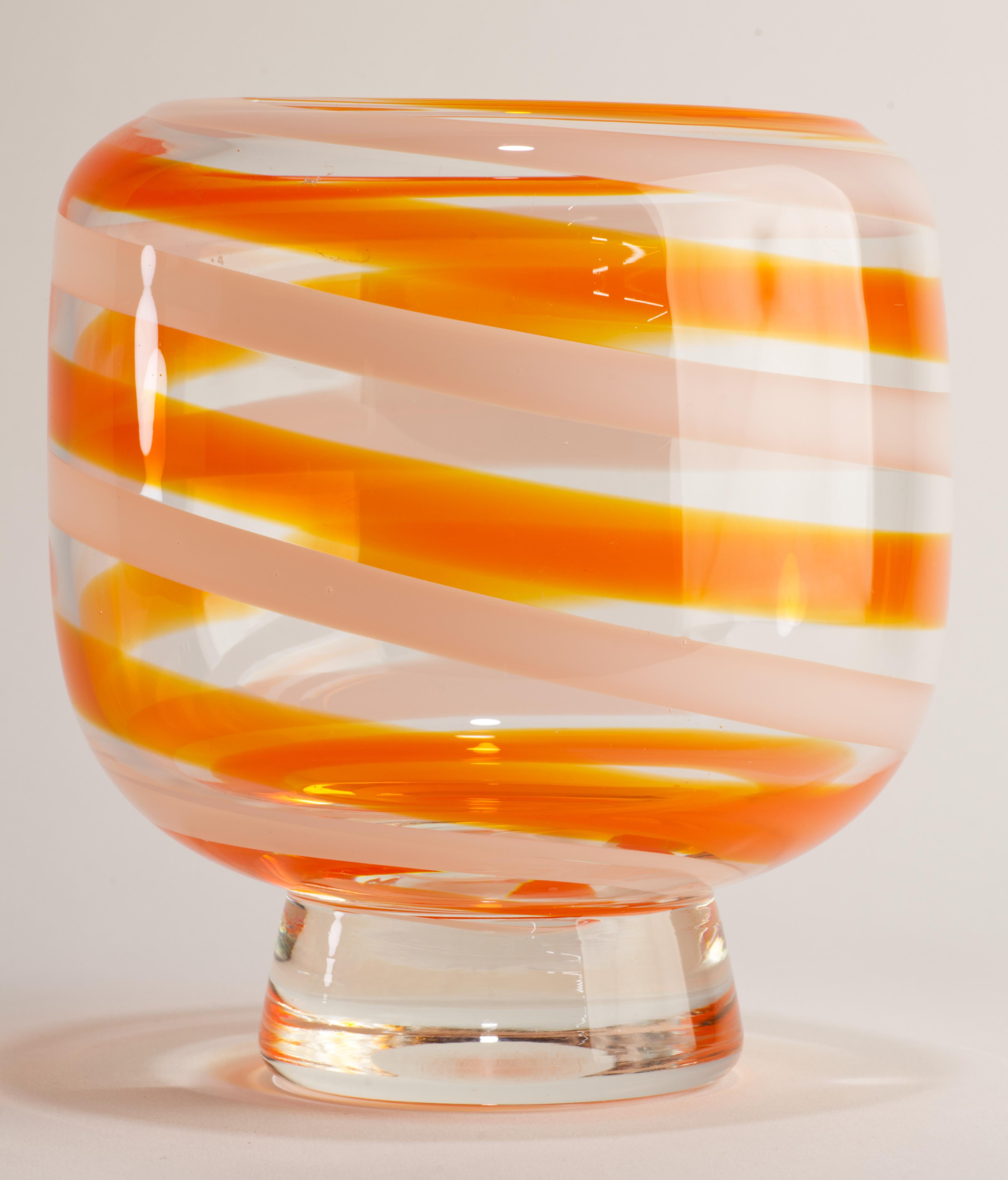 Il vaso scultoreo Whiting è decorato con linee vorticose di vetro fuso bianco e arancione trasparente, che girano intorno alla ciotola verso il bordo e guidano l'occhio lungo le curve del vaso. Lo strato di vetro colorato è racchiuso in vetro