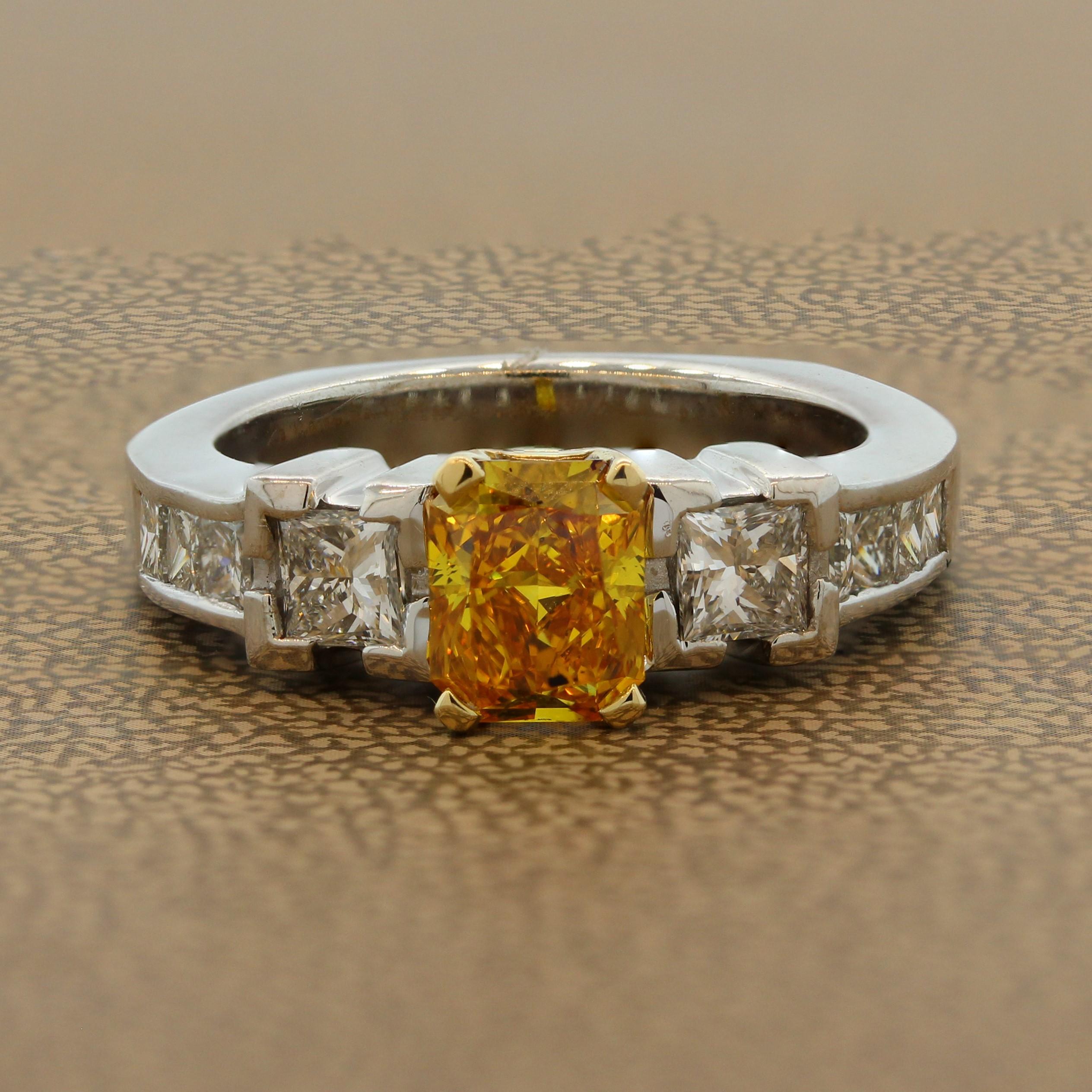 Stand out with an exquisite ring featuring a 1.01 carat orange-yellow diamond. The radiant cut diamond is accented by 1.10 carts of princess cut diamonds in a 14K white gold setting. There is great contrast between the vivid fancy color diamond and