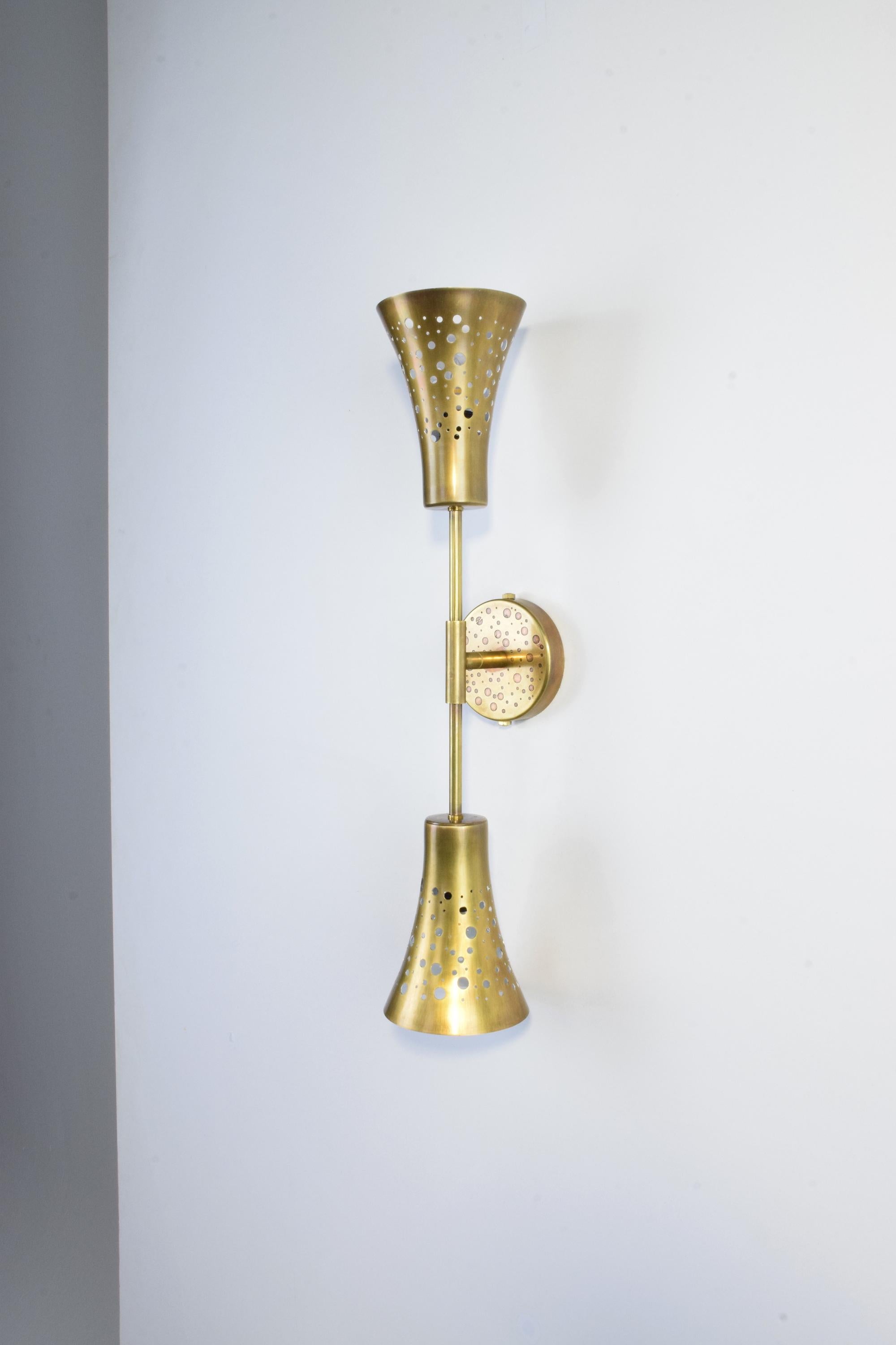 This wall light by Jonathan Amar Studio is a reference to the earth's circular shape; the ORBI-w2M1 is a symmetrical double shade in perforated brass that diffuses a soft light upwards and downwards. 
The same model with glass globes or without