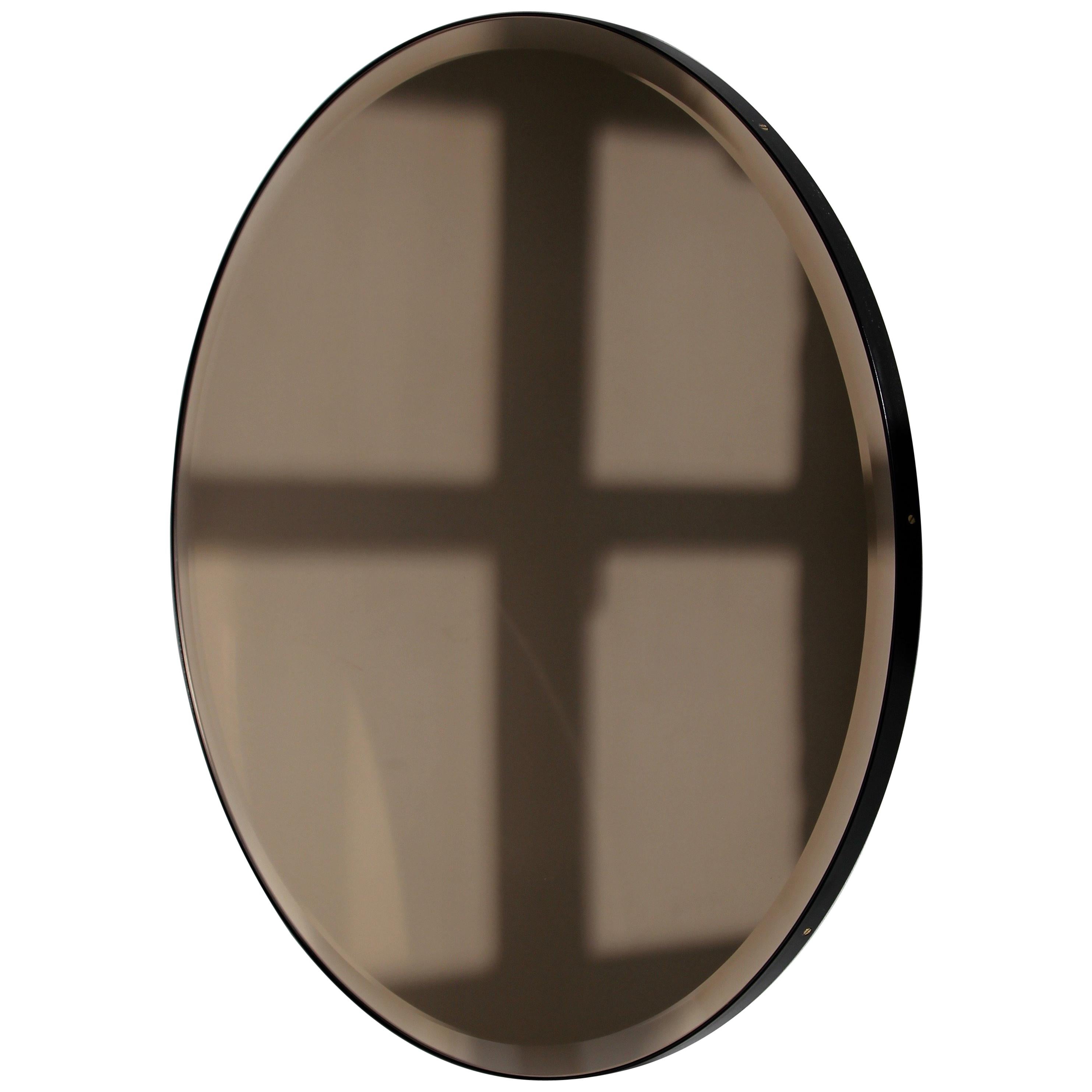 Dekorativer, bronzefarben getönter Orbis™-Rundspiegel mit elegantem Schliff und schwarzem, pulverbeschichtetem Aluminiumrahmen. Entworfen und handgefertigt in London, UK.

Unsere Spiegel sind mit einem integrierten französischen Befestigungssystem