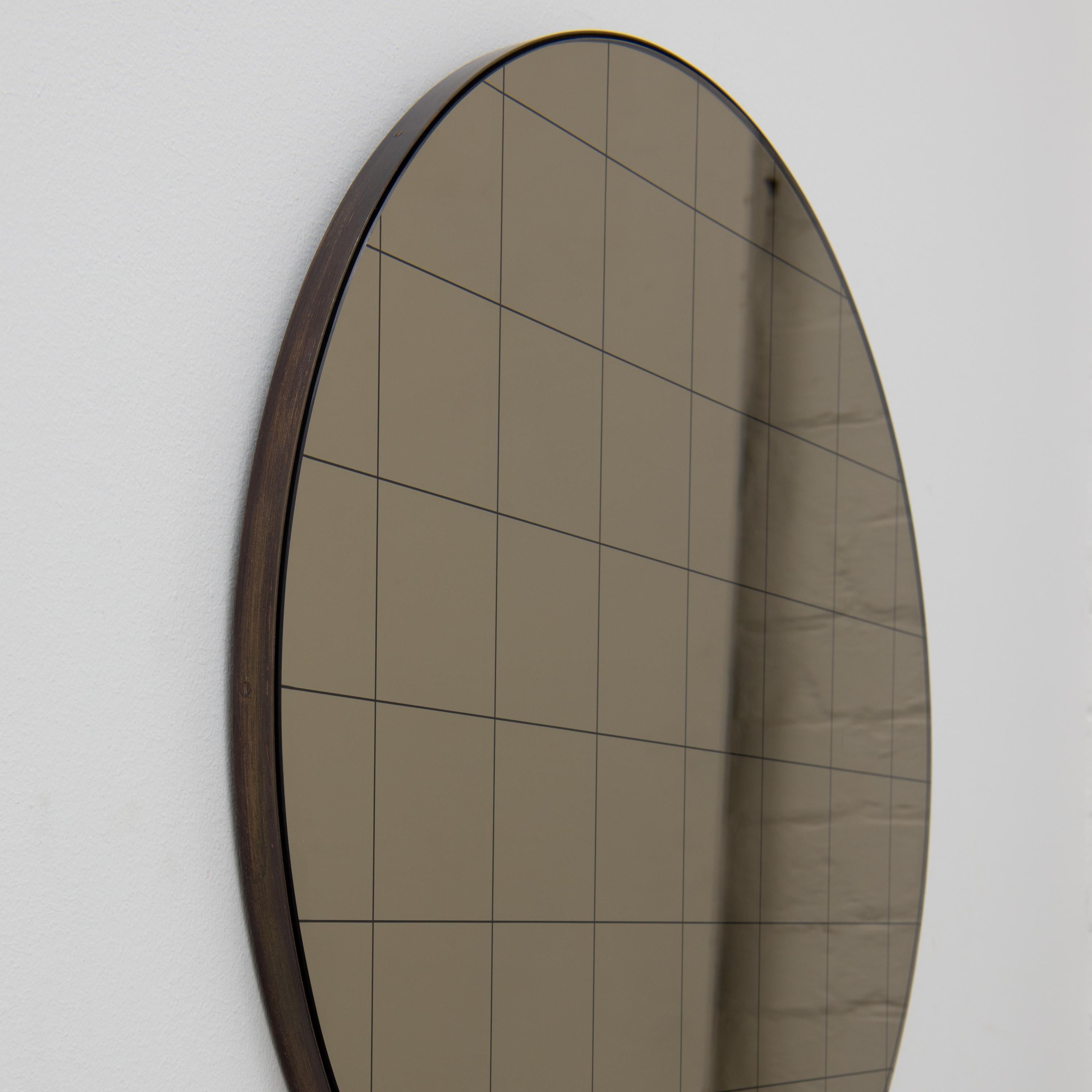 Modern round bronze mirror with an etched black grid and an elegant bronze patina brass frame. Designed and handcrafted in London, UK.

Fitted with a brass hook or an aluminium z-bar depending on the size of the mirror. Also available on demand with