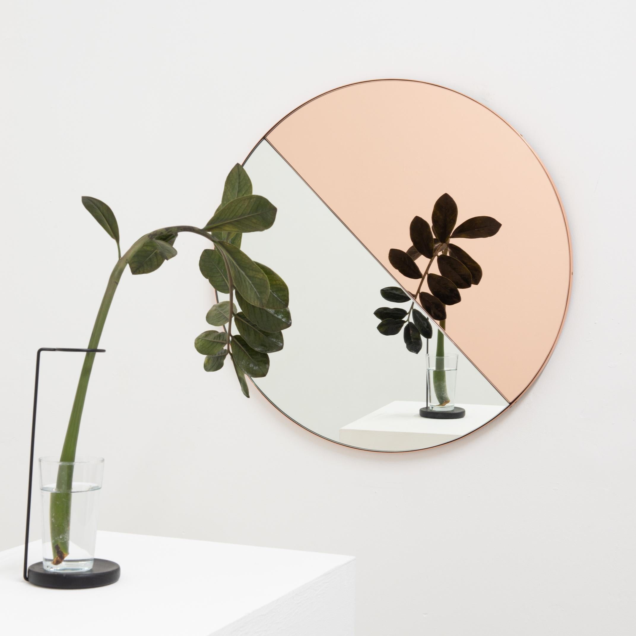 Miroir contemporain teinté mixte (argent et or rose/pêche) Orbis Dualis avec un cadre chic en cuivre. Conçu et fabriqué à la main à Londres, au Royaume-Uni.

Livré entièrement équipé d'un système d'accrochage spécialisé qui permet de suspendre le