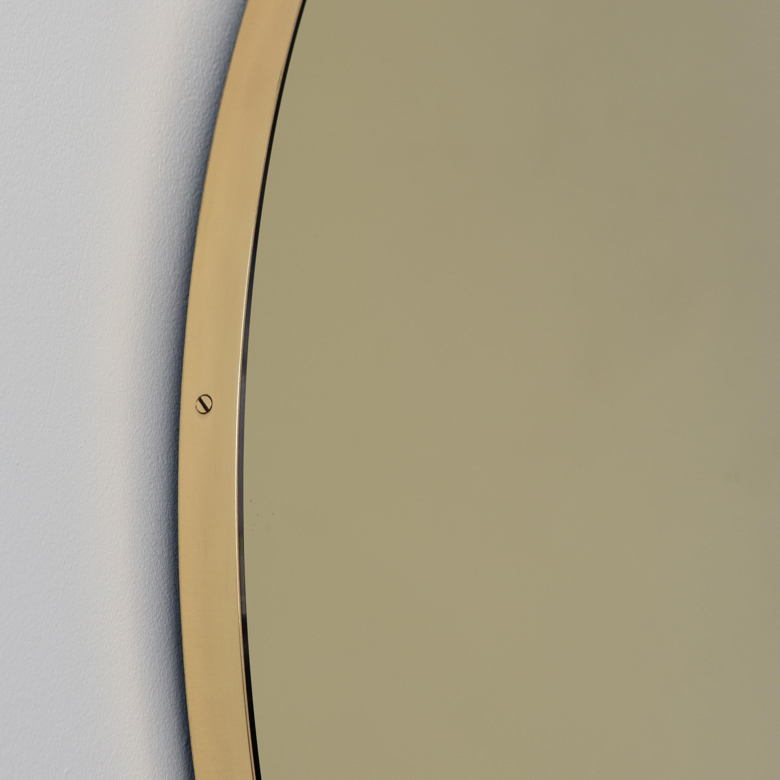 Wunderschöner runder Spiegel in Goldtönen mit einem eleganten, schlanken Rahmen aus gebürstetem Messing. Entworfen und handgefertigt in London, UK.

Die Details und die Verarbeitung, einschließlich der sichtbaren Messingschrauben, unterstreichen