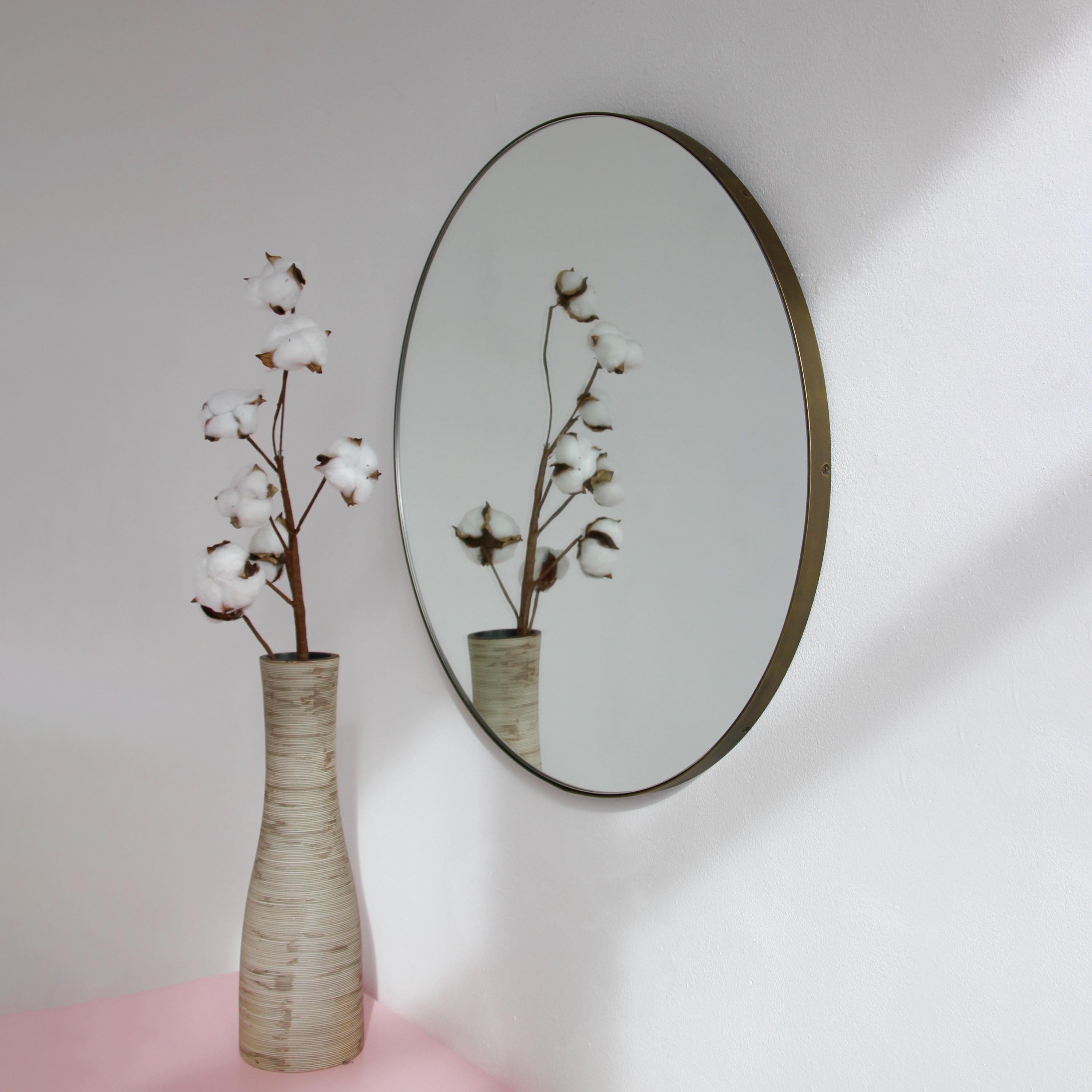 Miroir rond minimaliste Orbis™ avec un cadre en laiton massif à la finition patinée bronze. Les détails et la finition, y compris les vis apparentes, soulignent l'aspect artisanal et la qualité du miroir, véritable signature de notre marque. Conçu