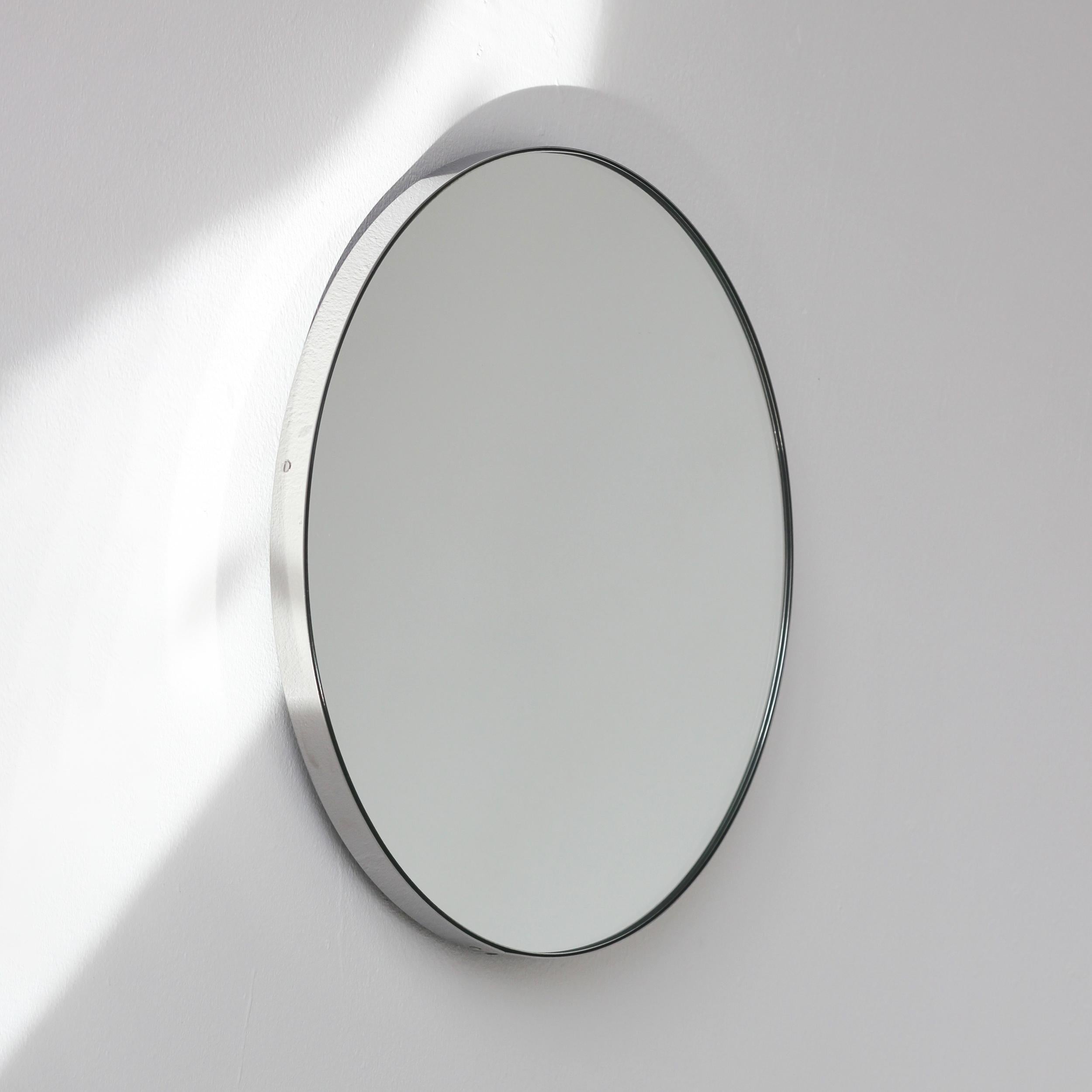 Miroir rond minimaliste Orbis™ avec un élégant cadre en acier inoxydable brossé (également disponible en finition polie). Les détails et la finition, y compris les vis apparentes, soulignent l'aspect artisanal et la qualité du miroir, véritable