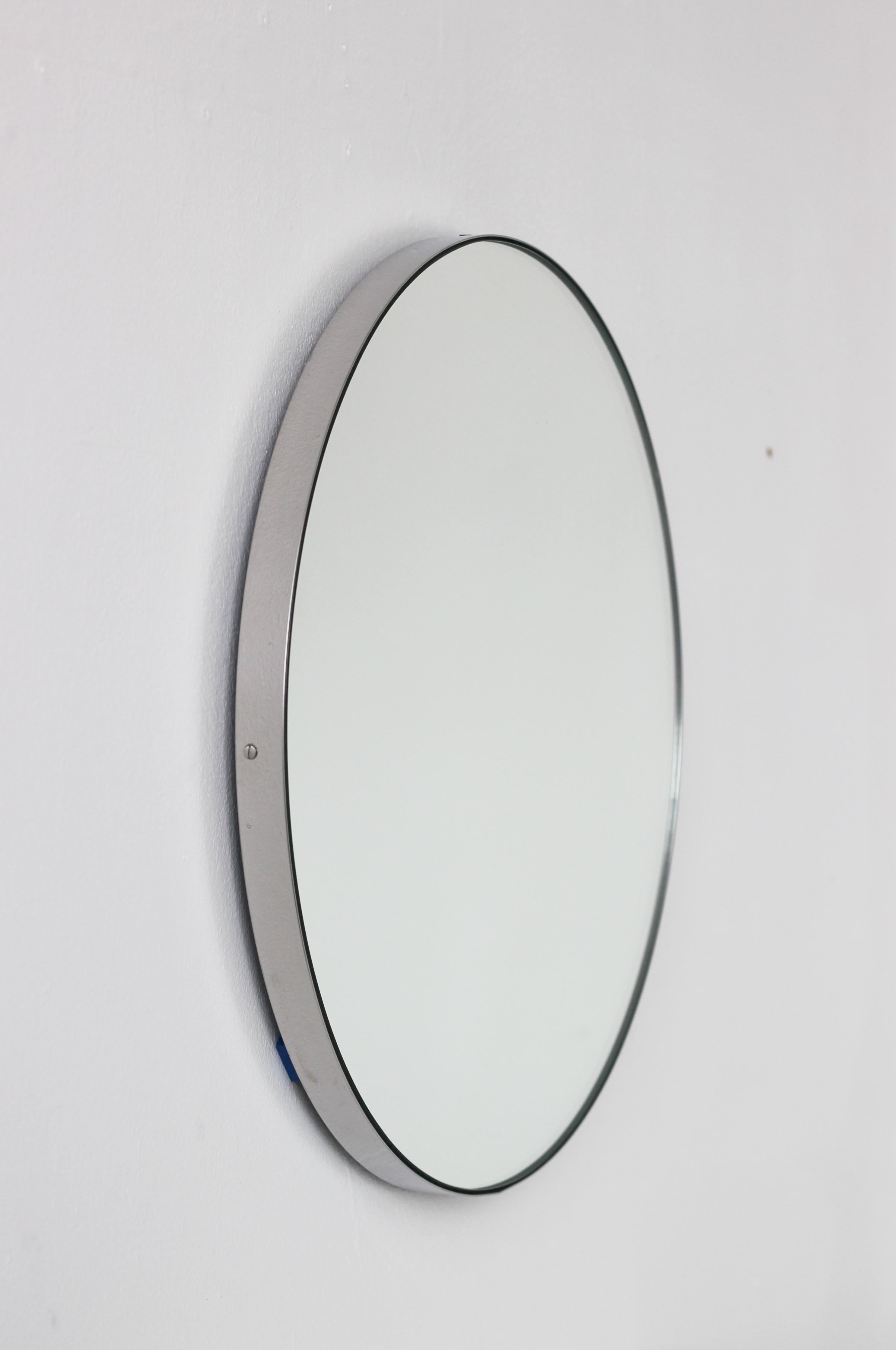 Minimalistischer runder Spiegel mit einem eleganten Rahmen aus gebürstetem Edelstahl (auch in polierter Ausführung erhältlich). Die Details und die Verarbeitung, einschließlich der sichtbaren Schrauben, unterstreichen die handwerkliche und