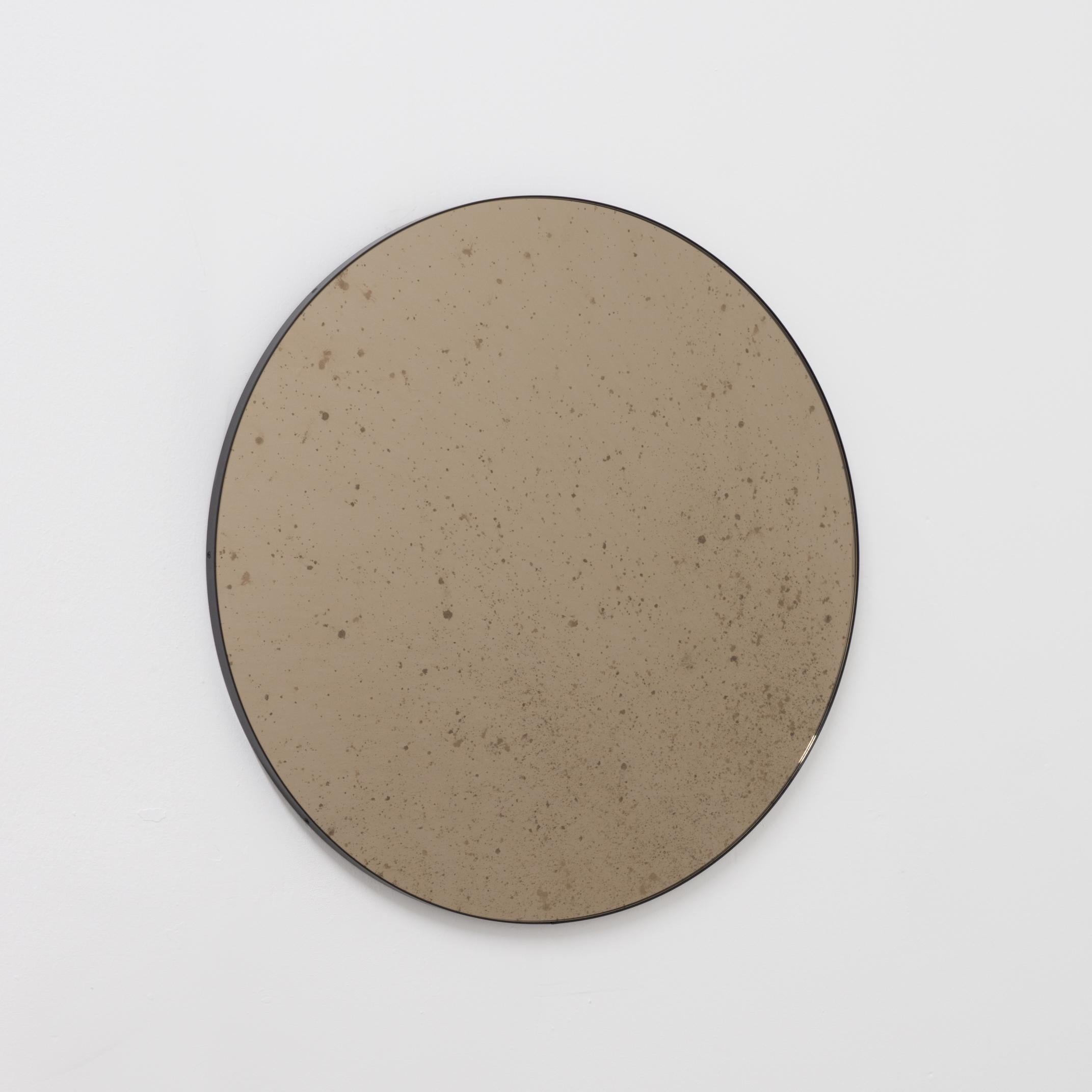 Delightful bronze tinted antiqued round mirror with an elegant black frame. Designed and handcrafted in London, UK.

Medium, large and extra-large mirrors (60, 80 and 100cm) are fitted with an ingenious French cleat (split batten) system so they may