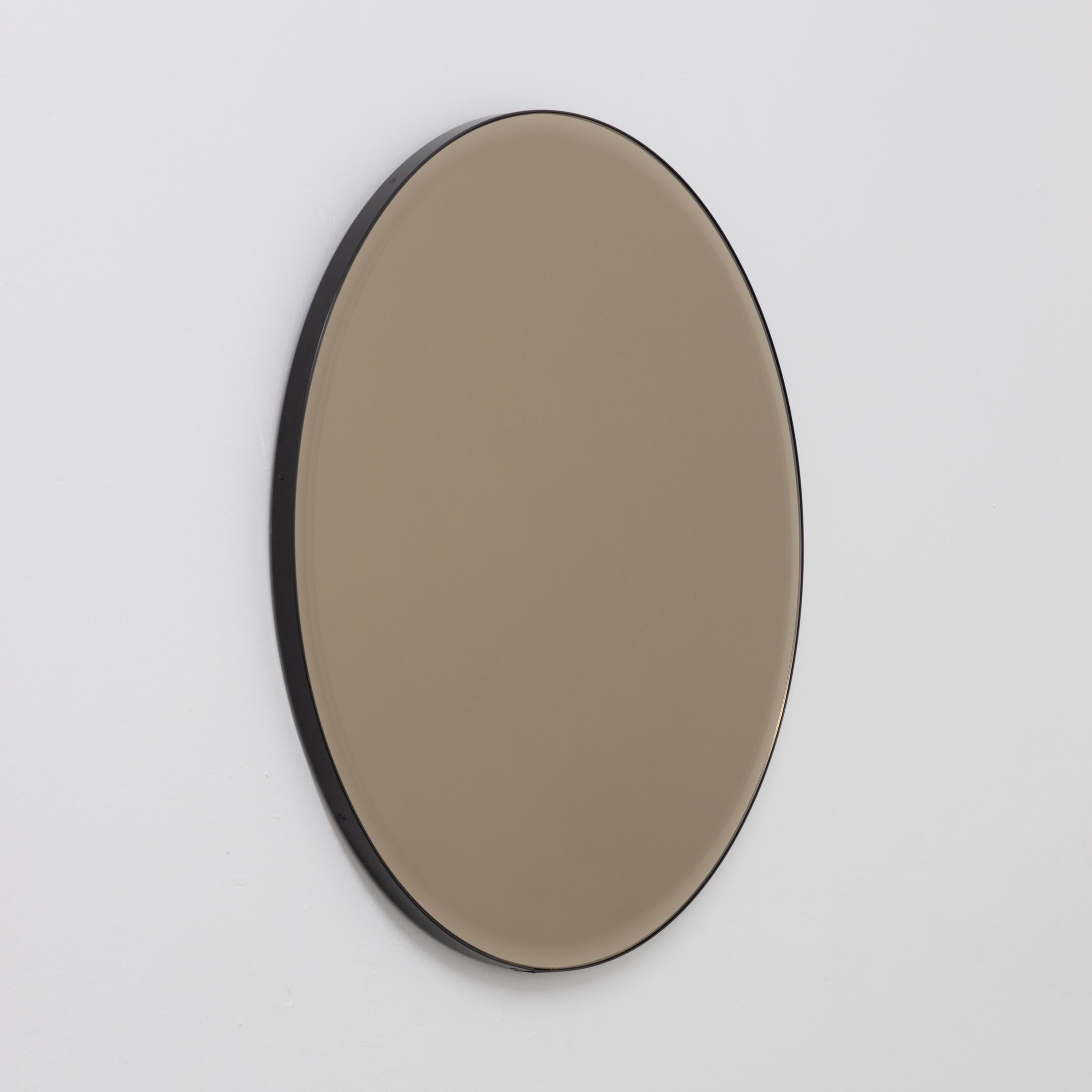 Decorative bevelled bronze tinted round mirror with an elegant aluminium powder coated black frame. Designed and handcrafted in London, UK.

Medium, large and extra-large mirrors (60, 80 and 100cm) are fitted with an ingenious French cleat (split