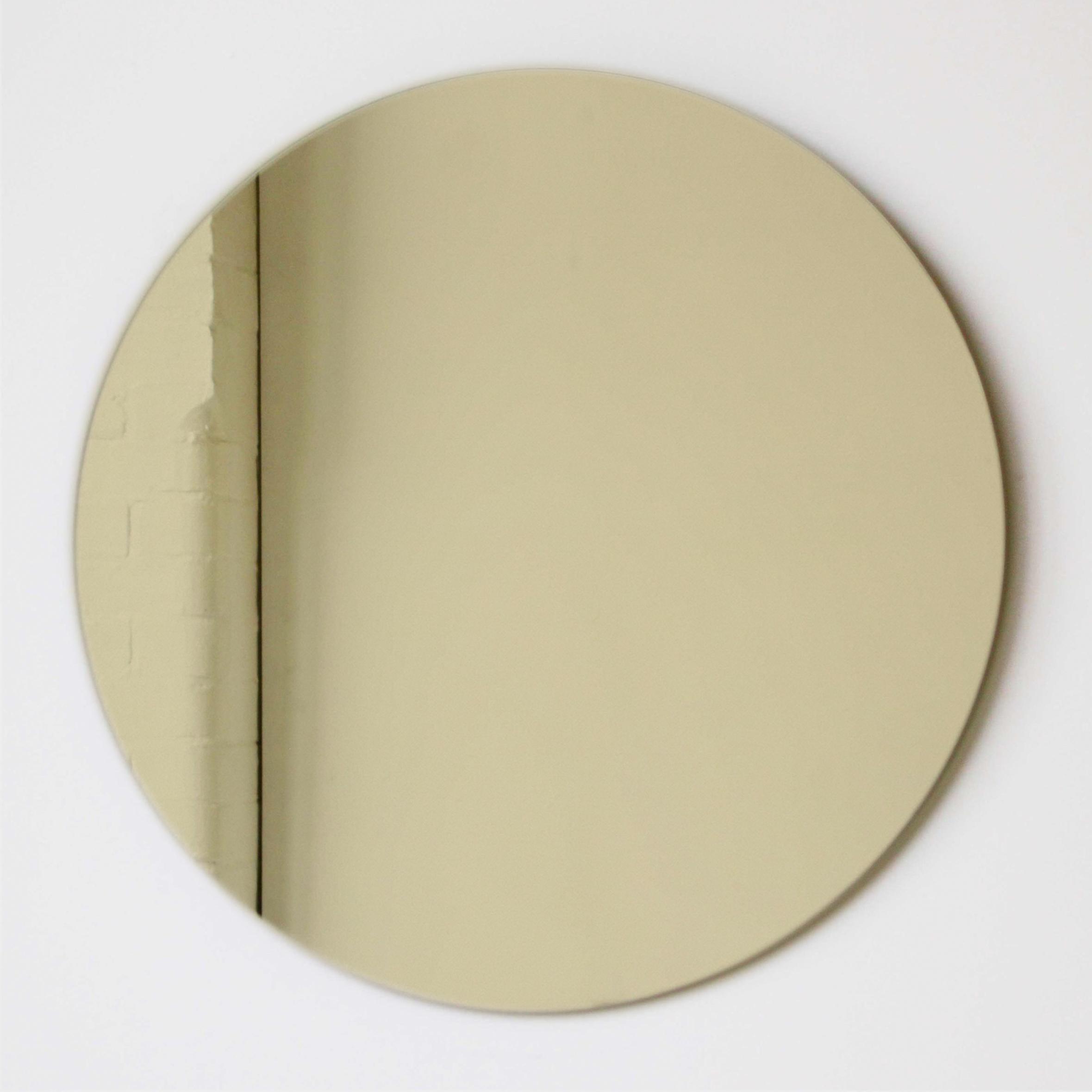 Charmant et minimaliste miroir rond sans cadre teinté d'or avec un effet flottant. Un design de qualité qui garantit que le miroir est parfaitement parallèle au mur. Conçu et fabriqué à Londres, au Royaume-Uni.

Equipé de plaques professionnelles