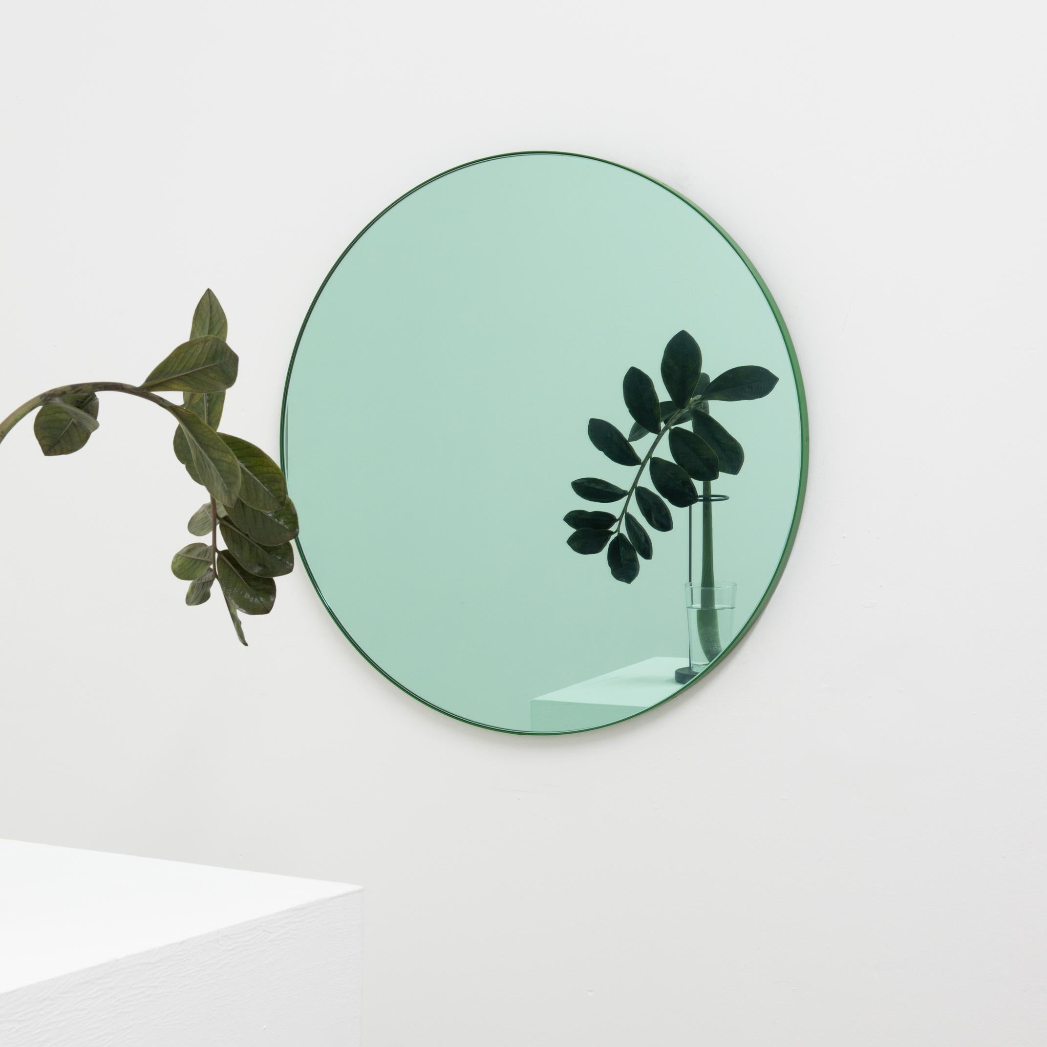 Delightful round green tinted mirror with a colorful green powder coated aluminum frame.

Designed and handcrafted in London, UK. The detailing and finish, including visible brass or green screws, emphasize the craft and quality feel of the mirror,