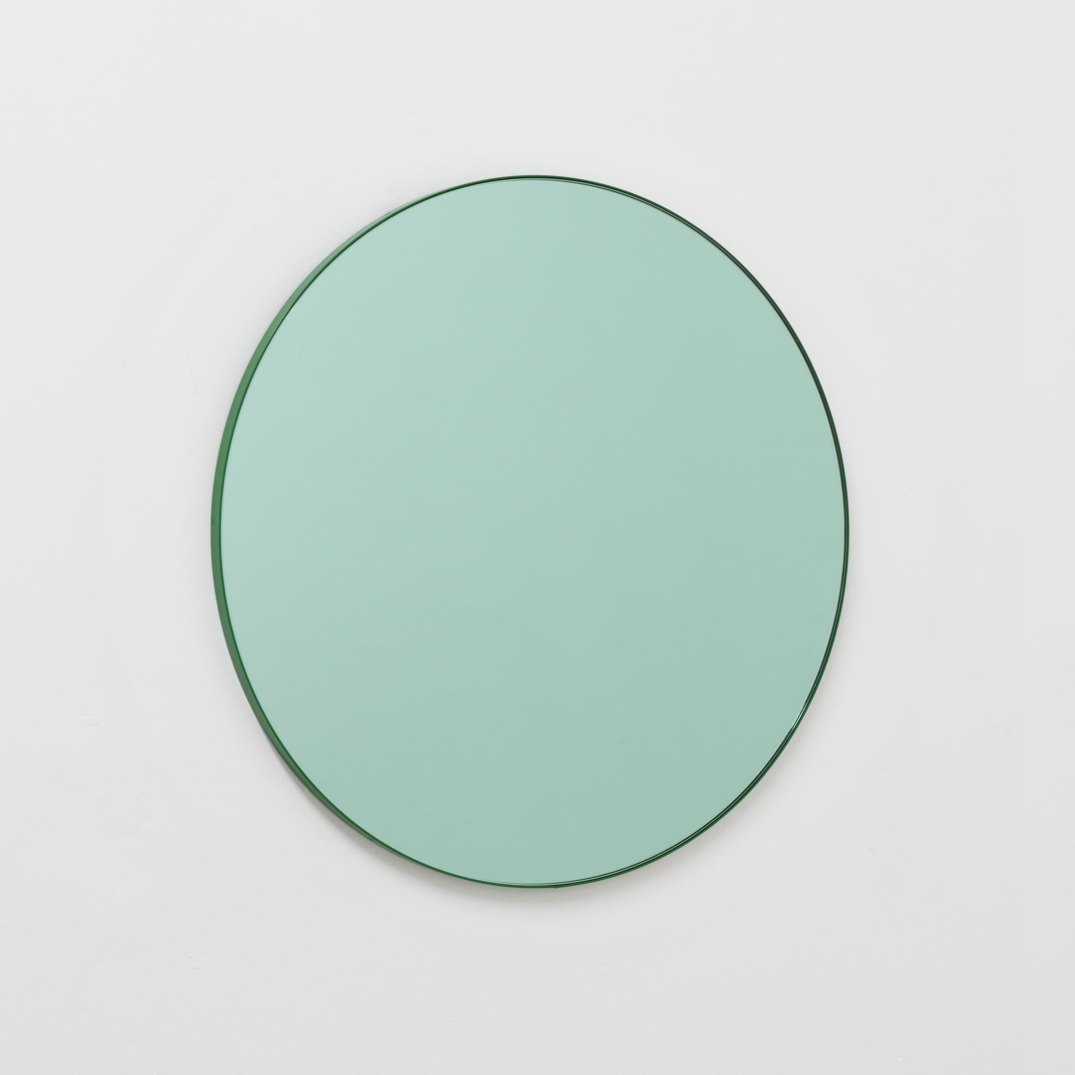 Delightful round green tinted mirror with a colorful green powder-coated aluminium frame.

Designed and handcrafted in London, UK. The detailing and finish, including visible brass screws, emphasize the craft and quality feel of the mirror, a true