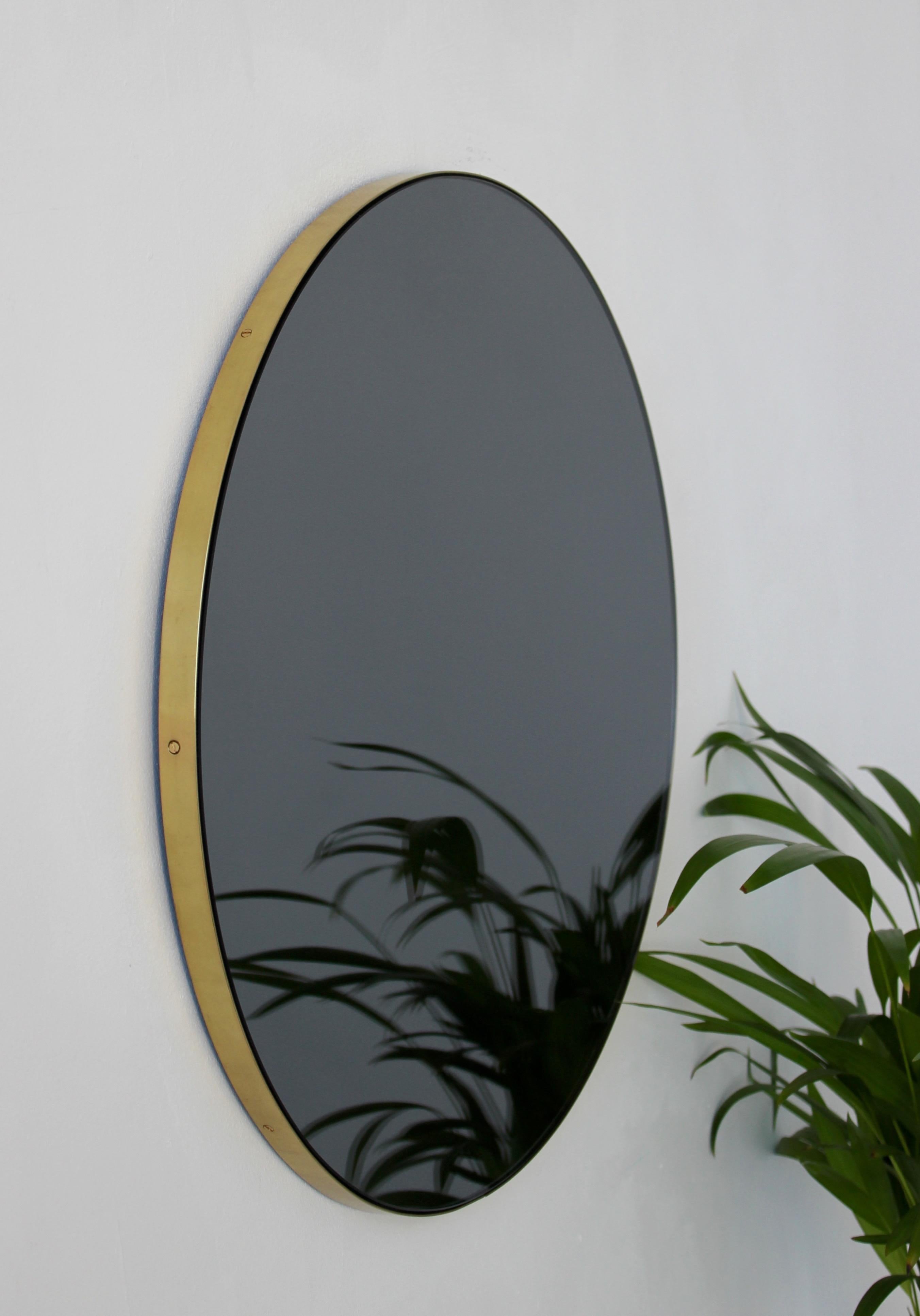 Minimalist black tinted round mirror with an elegant brushed brass frame. The detailing and finish, including visible brass screws, emphasise the crafty and quality feel of the mirror, a true signature of our brand. Designed and handcrafted in