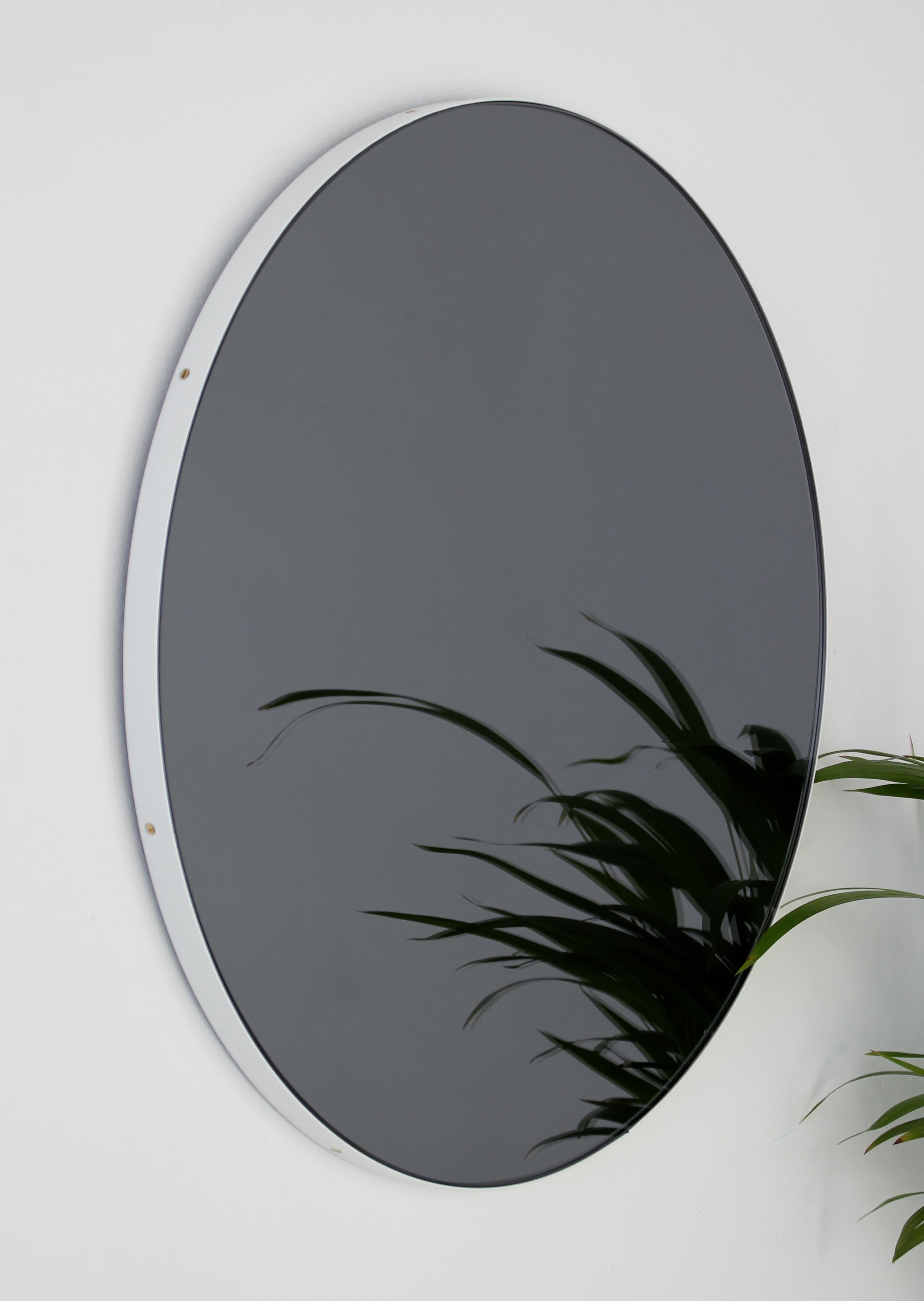 Contemporary black tinted round mirror with a smart white powder coated aluminium frame. Designed and handcrafted in London, UK.

Fitted with a brass hook or an aluminium z-bar depending on the size of the mirror. Also available on demand with a