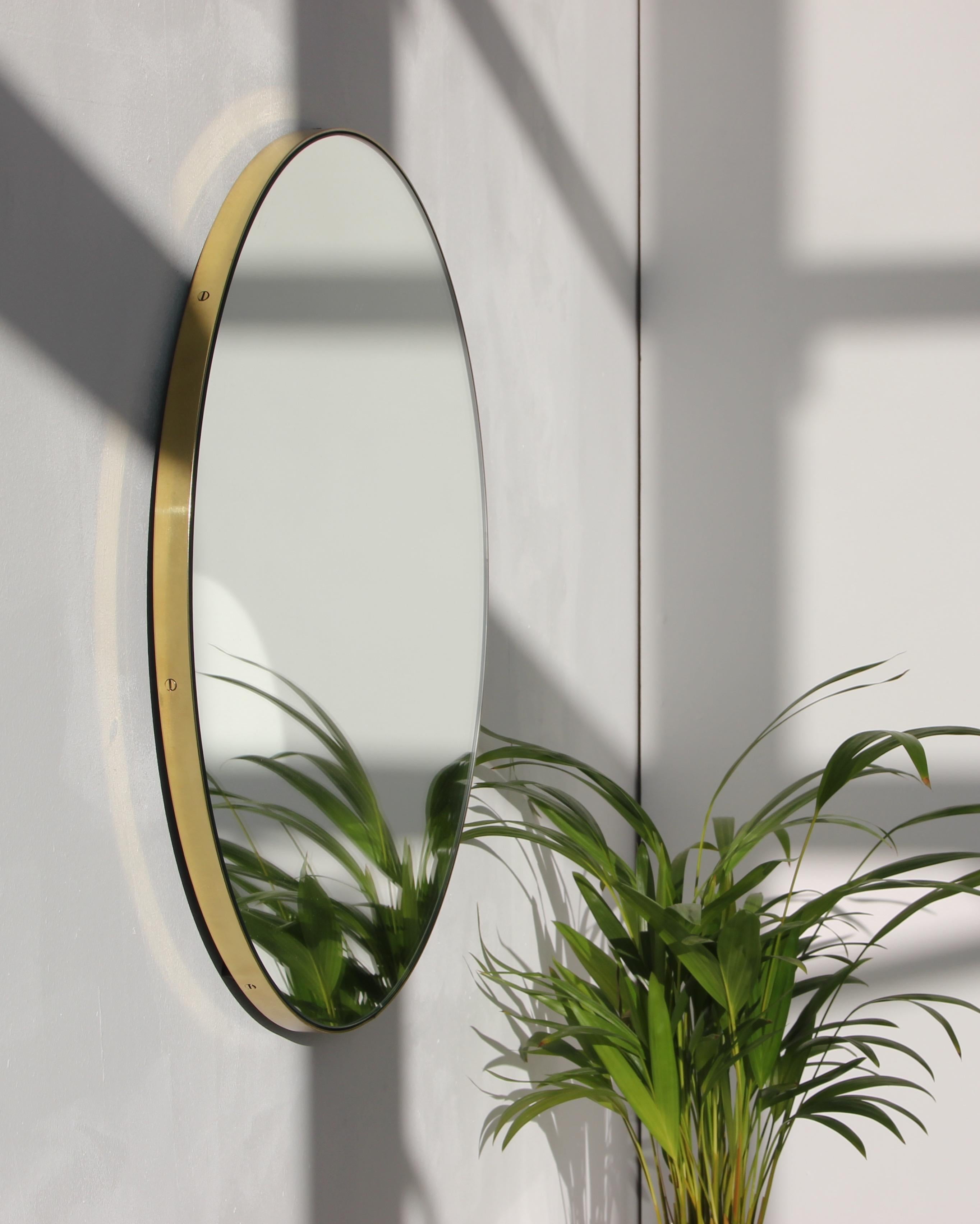 Minimalistischer runder Orbis™-Spiegel mit einem eleganten Rahmen aus gebürstetem Messing. Die Details und die Verarbeitung, einschließlich der sichtbaren Messingschrauben, unterstreichen die handwerkliche Qualität des Spiegels, ein echtes