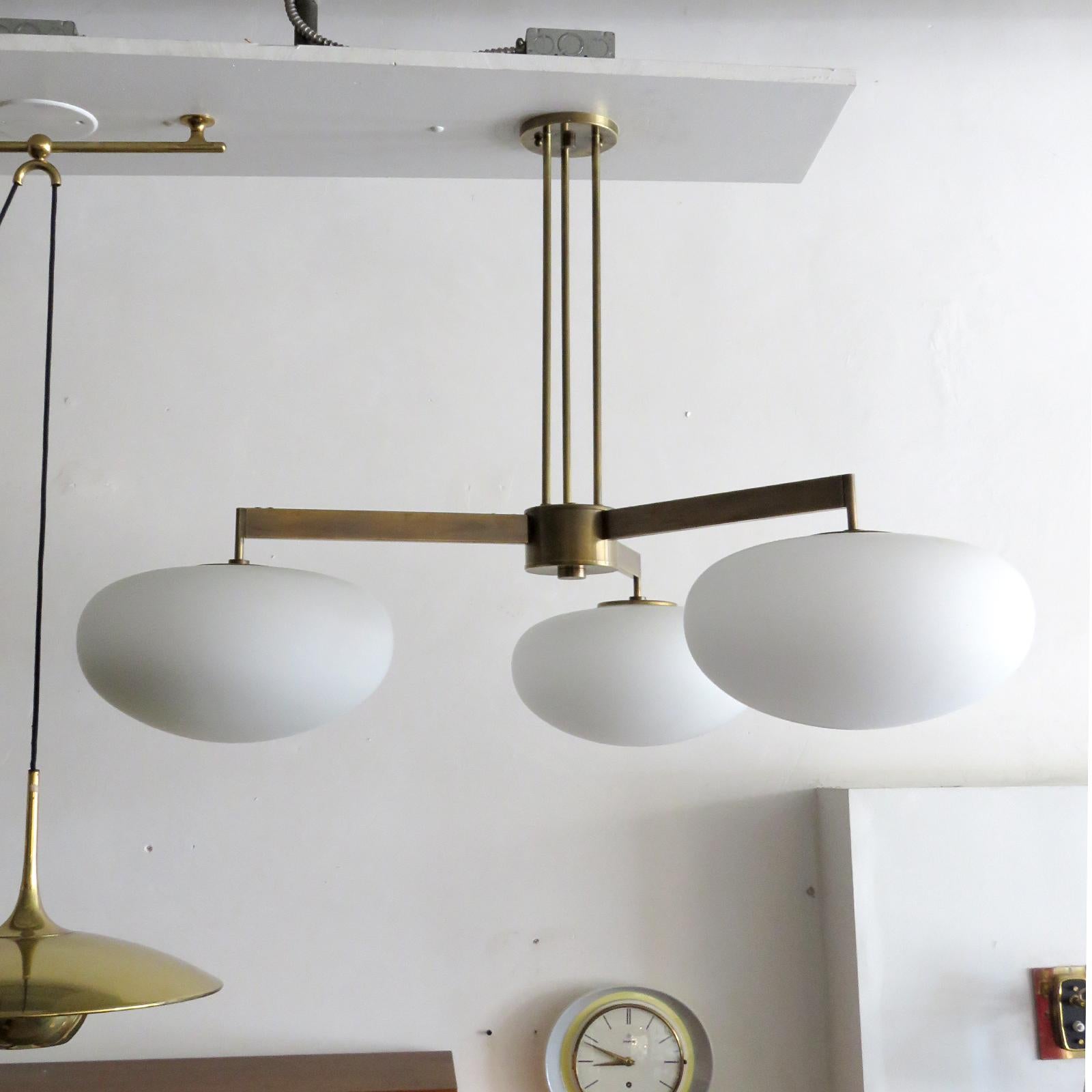 stunning large-scale three-arm chandelier by Gallery L7, handcrafted and finished in Los Angeles from American brass with aged brass finish and three matte opaline glass globes, measures 30 x 40 inch (h x d), height can be customized per request,