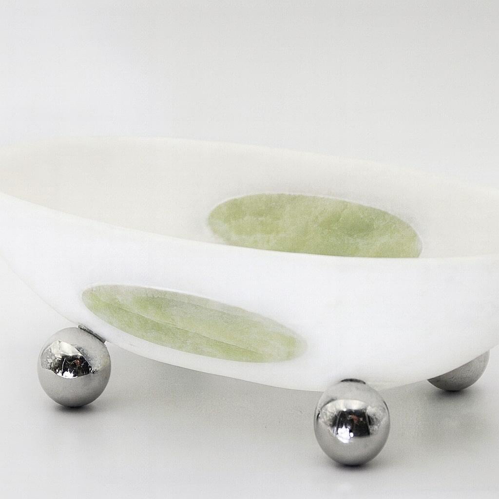 A sculptural centerpiece carved from solid white Onyx, this bowl celebrates the quiet elegance of natural stone. Its soft oval silhouette reveals delicate mineral veining. A subtle green marble inlay on the outer wall introduces a refined contrast, 