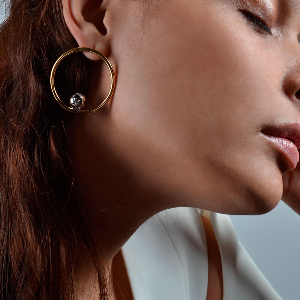 A unique set of Hoop Earrings inspired by the Earth's Orbit, featuring an ellipse with small cut out the globe in the middle as the perfect balance. Available in double color finished 24K Gold Plated Brass and Rhodium Plated. An elegant accessory