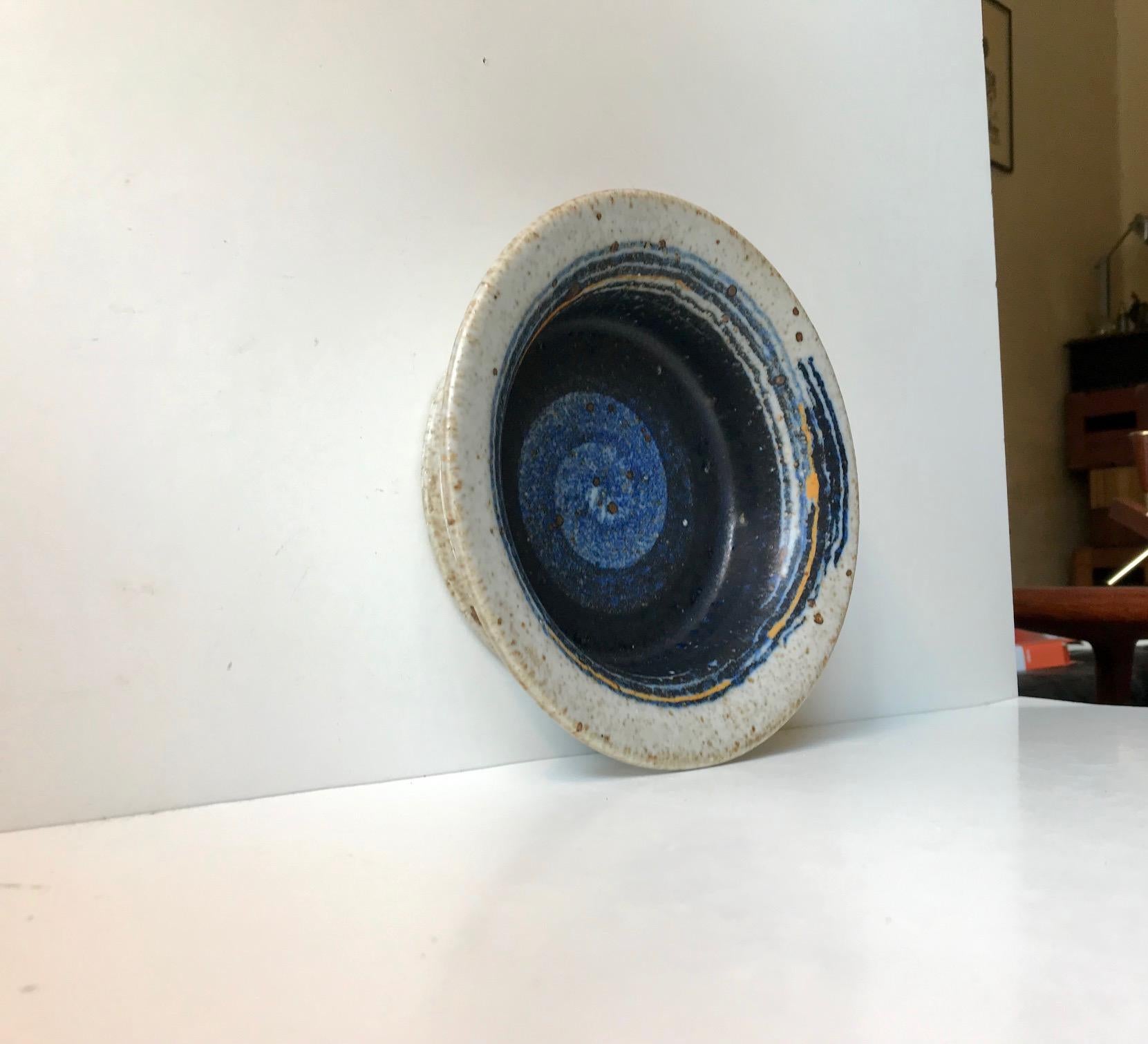 - Plat ou bol unique en grès avec motif orbitale en glaçure gris moucheté, bleu, noir et jaune
- Conçu par Inge Persson dans les années 1960 au studio Rorstand - Atelje
- Marques peintes à la main : 