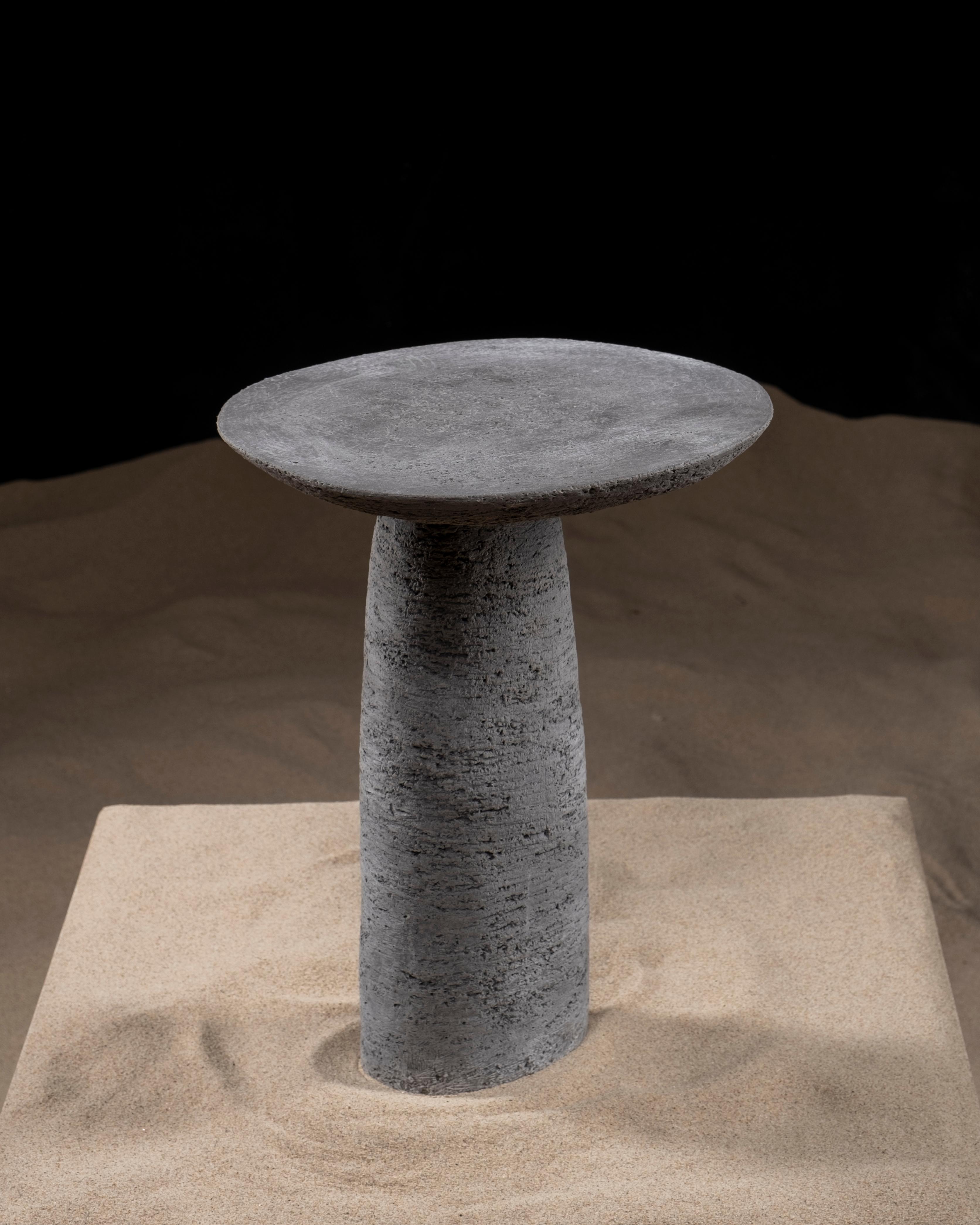 Der Beistelltisch Orbitae ist ein skulpturales Möbelstück aus Keramik. Der Designer ließ sich von der Umlaufbahn und den Wellenbewegungen inspirieren, suchte nach einer physischen Form und wollte mit Orbitae einen Moment des Zyklus einfangen. Sie