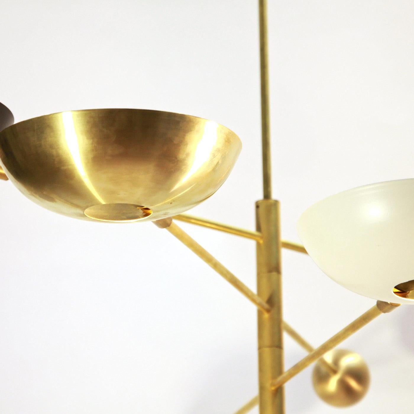 Questo elegante lampadario a tre bracci rende omaggio al dinamismo delle orbite dei pianeti. La struttura in ottone verniciato a polvere è composta da tre bracci rotanti che si estendono orizzontalmente da uno stelo verticale; ogni braccio sostiene
