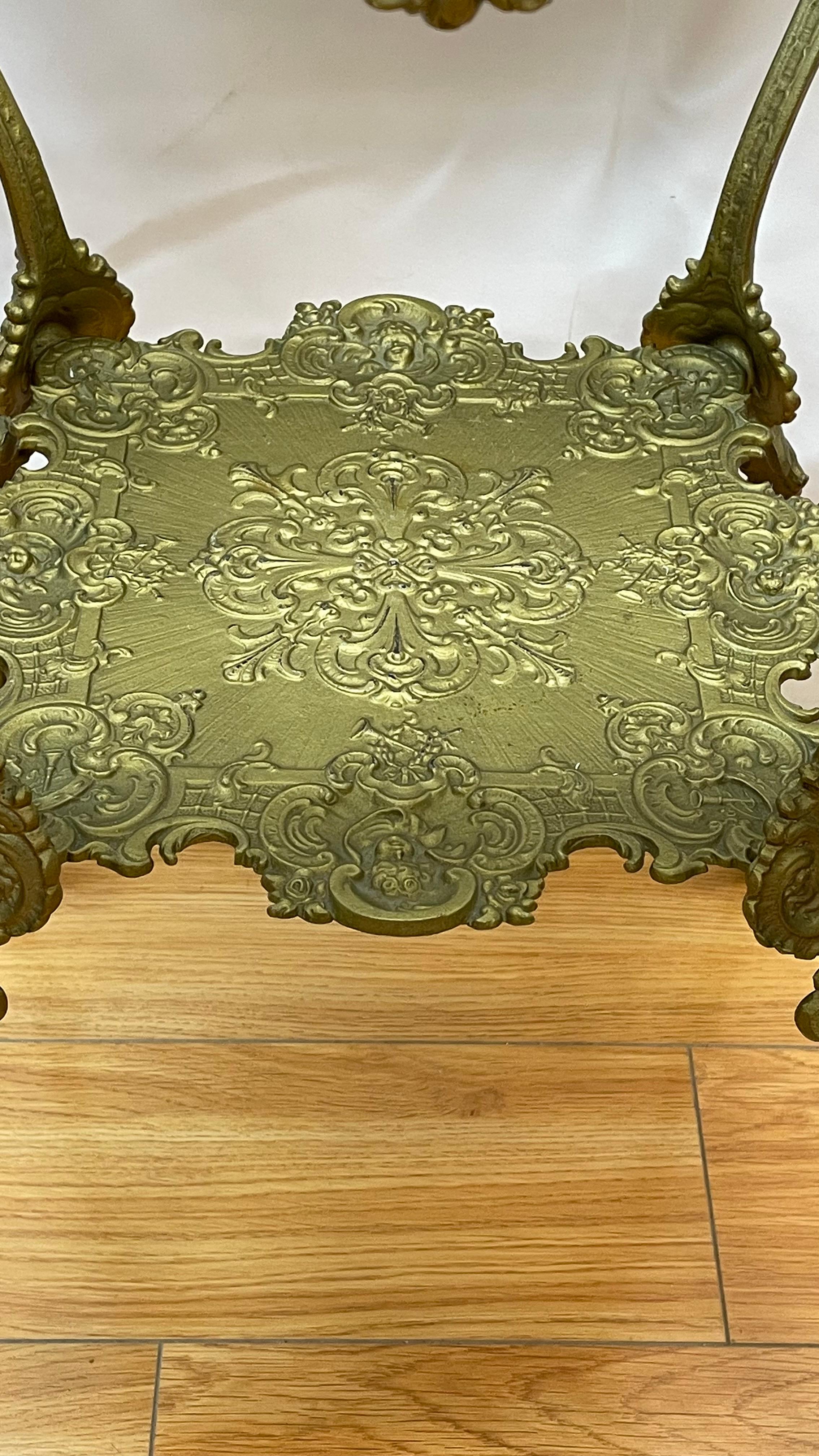Ornate 1920's brass two-tier table with glass top decorated with cherubs 