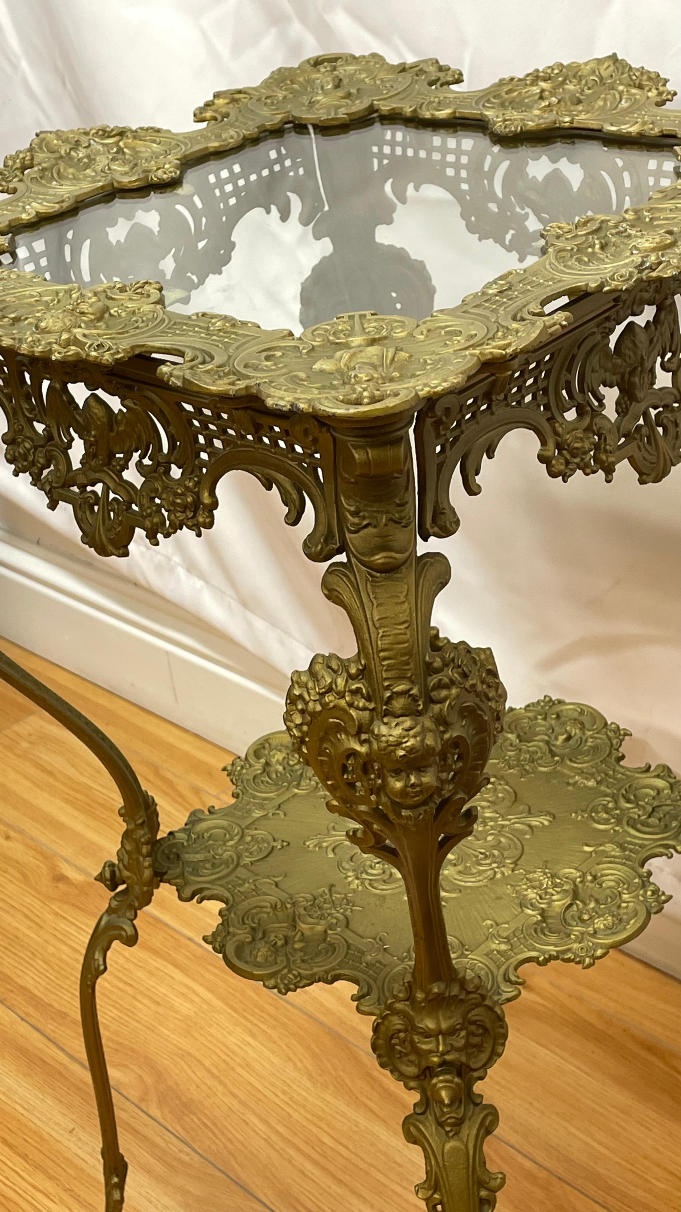 Laiton Table ornée des années 1920 à deux niveaux en laiton avec plateau en verre décoré d'angelots  en vente