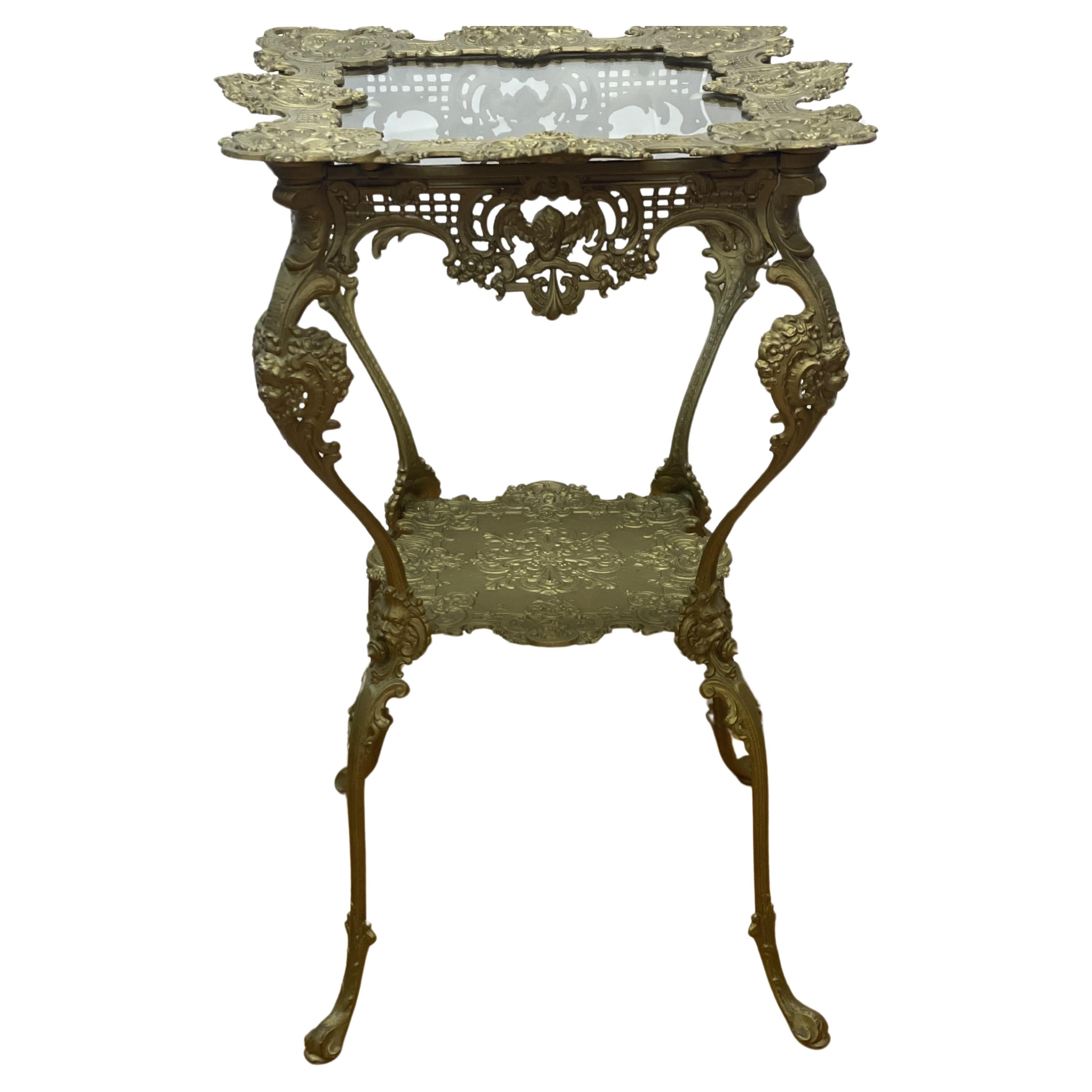 Ornate 1920's Two-Tier Brass Table w/Glass Top decorated with cherubs  For Sale