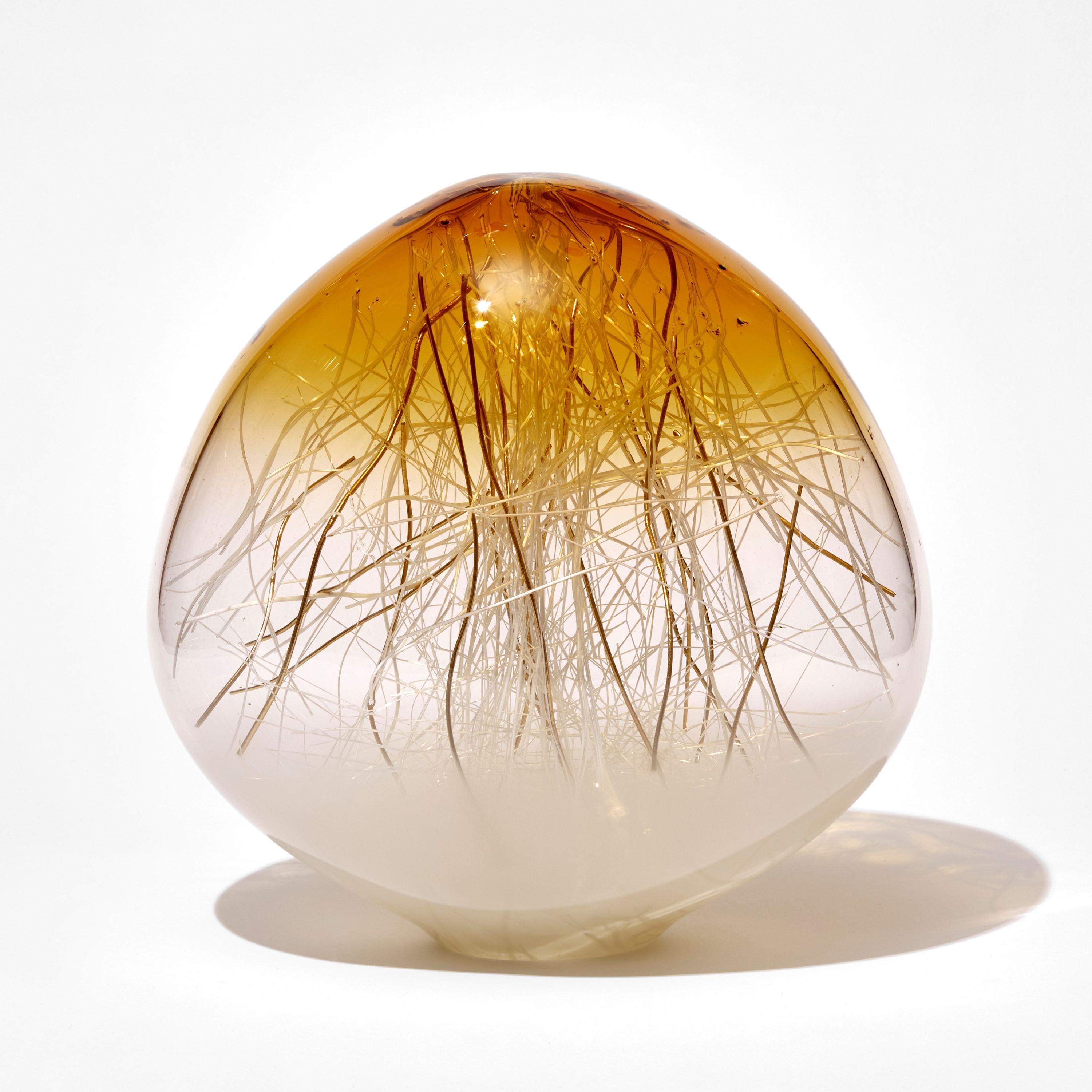 'Ore in Amber & Ecru with Gold' is a unique glass sculpture by the collaborative artists Hanne Enemark (Danish) and Louis Thompson (British). The outer glass form contains a multitude of fine white canes of glass, some of which have been coated in