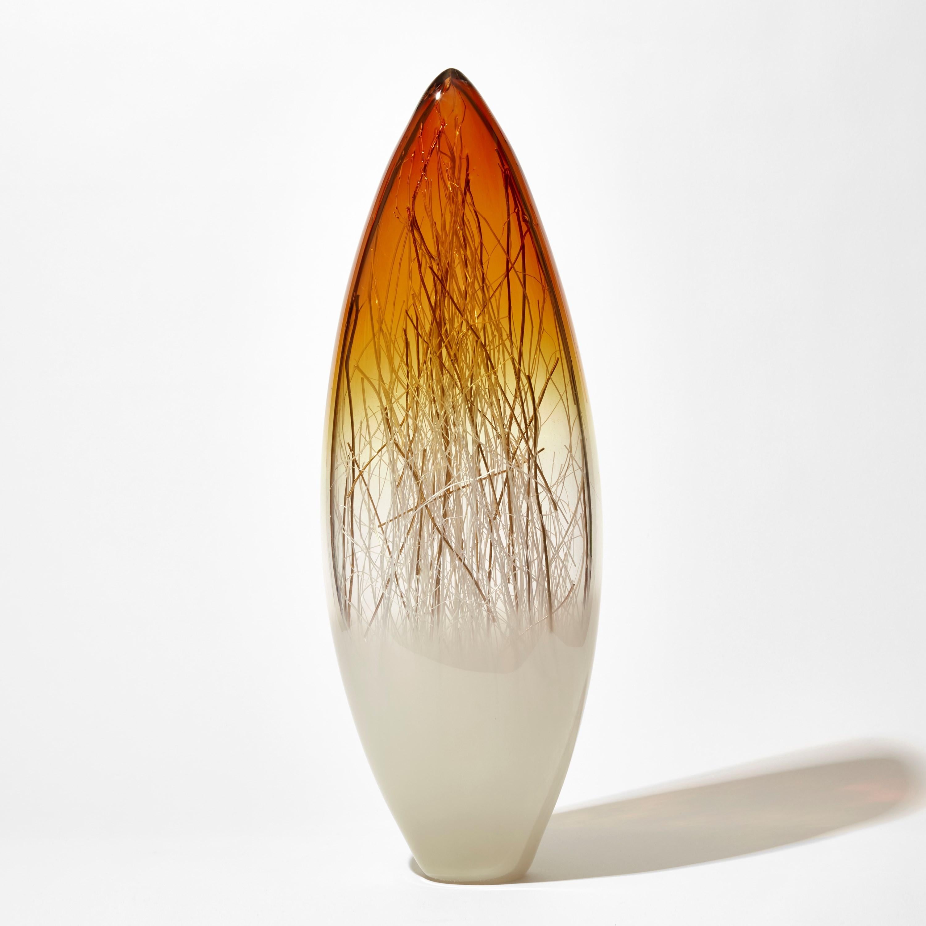 'Ore in Amber & Ecru with Gold' is a unique handblown and sculpted glass artwork by the Danish and British artists, Hanne Enemark & Louis Thompson.

The outer glass form contains a multitude of fine white canes of glass, some of which have been