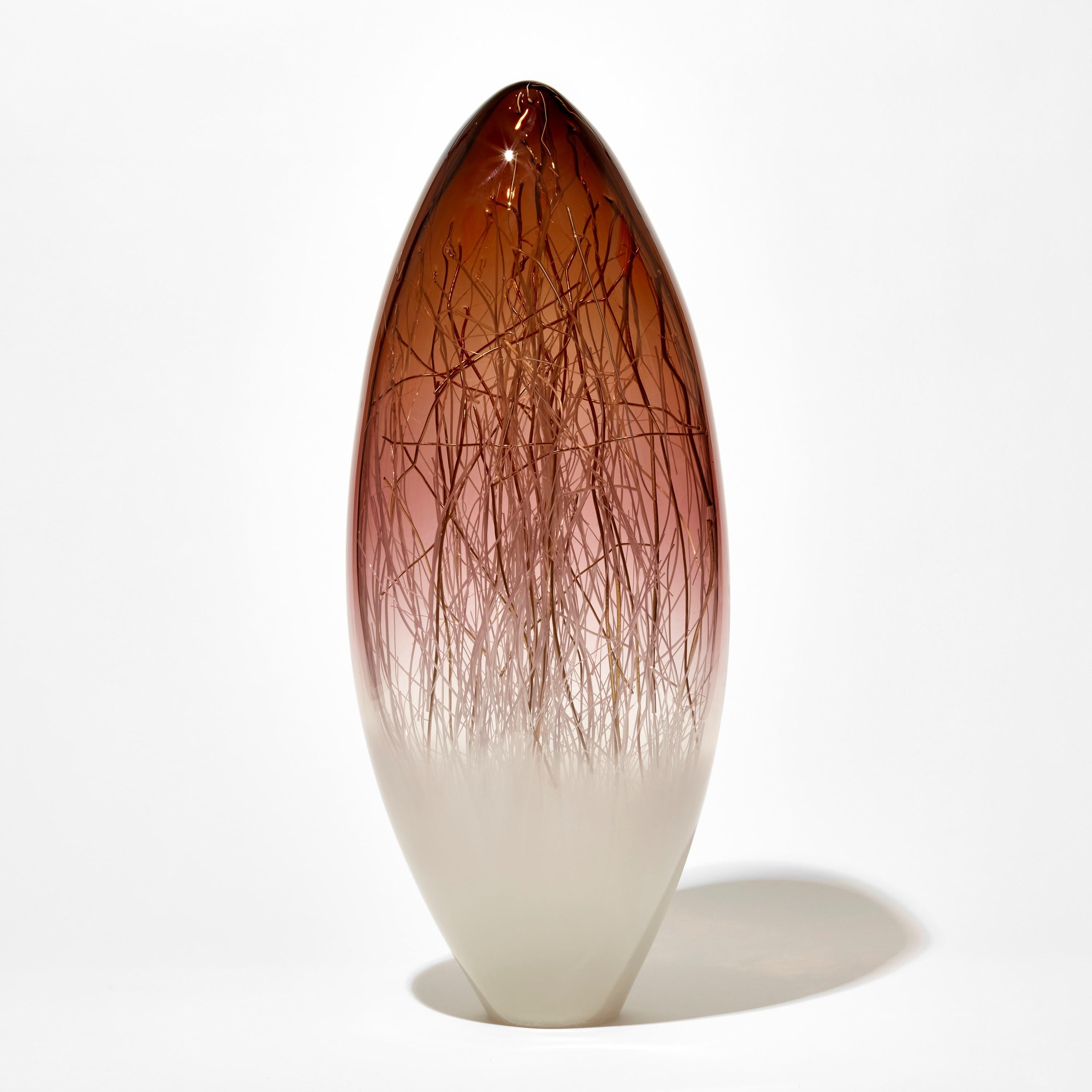 'Ore in Sienna & Ecru with gold' is a unique glass sculpture in aubergine and off-white colored glass by the collaborative artists Hanne Enemark (Danish) and Louis Thompson (British). The outer glass form contains a multitude of fine white canes of