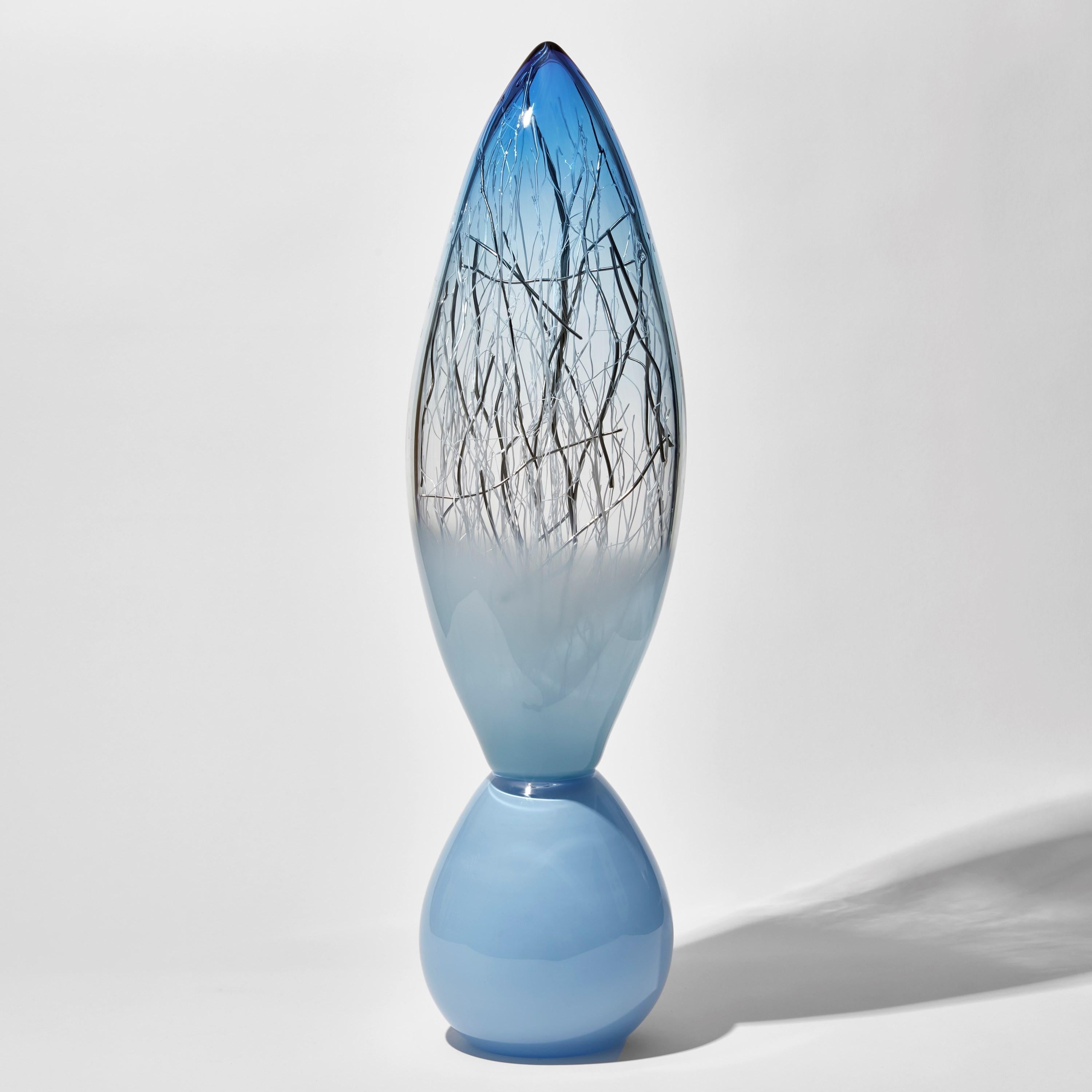 'Ore Totem in Aquamarine & Pale Turquoise with Platinum' is a unique glass sculpture by the collaborative artists Hanne Enemark (Danish) and Louis Thompson (British). The outer glass form contains a multitude of fine white canes of glass, some of