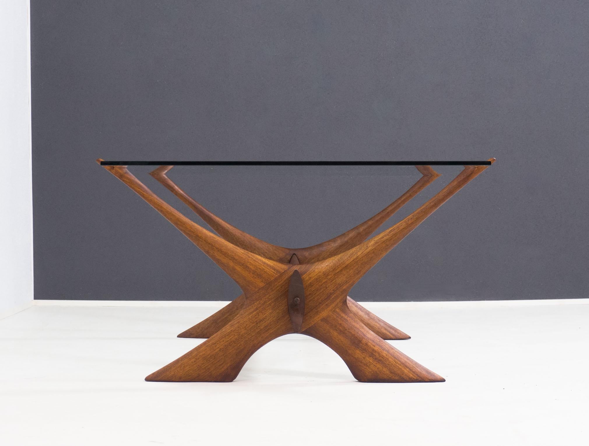 Impressive coffee table designed by Fredrik Schriever-Abeln and made by Örebro Glas of Sweden in the 1960s.

This coffee table that is known as ‘Condor’ is made from a solid walnut X-shaped base that carries a 1 cm thick clear glass plate.

The