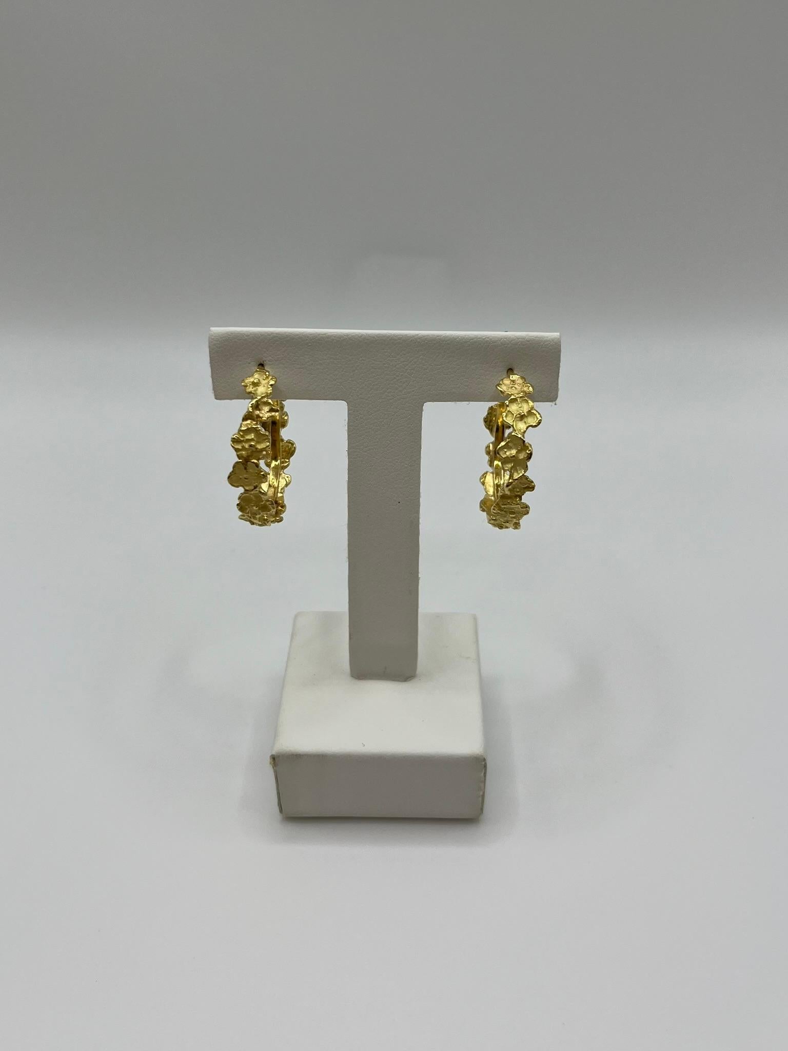 Elegantes pendientes de aro realizados íntegramente en oro amarillo de 18 kt. 750/00. Se han diseñado y fabricado a mano en Italia y presentan un relieve especial que dibuja flores a lo largo del círculo. El cierre es clásico, práctico y seguro. El