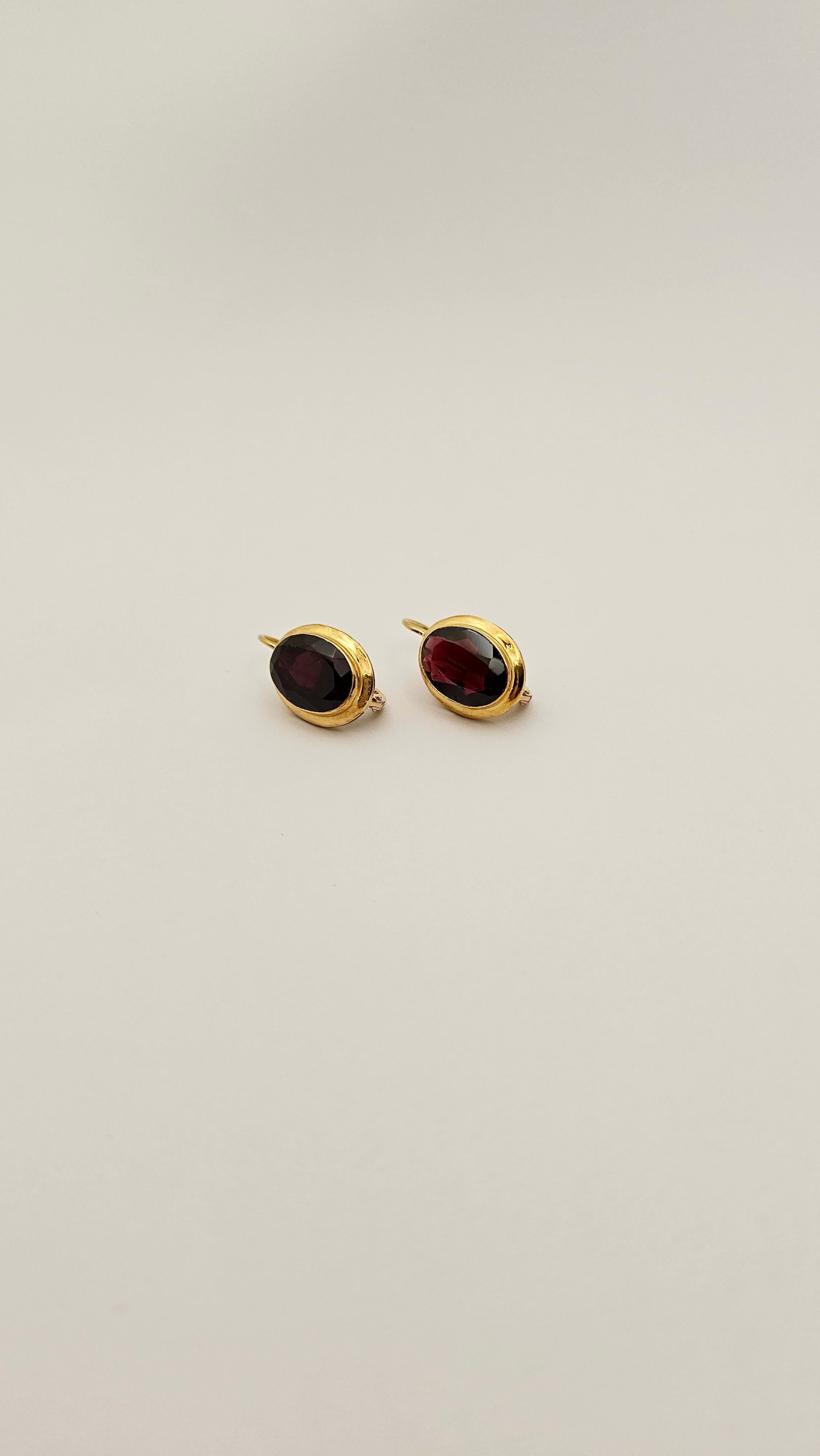 Un par de pendientes clásicos y elegantes.
Su diseño refinado y lineal los hace perfectos para llevarlos en cualquier ocasión.
De oro de 18 quilates y granate rojo intenso  talla oval facetada.
Esta joya de los años 50 está en perfecto estado, como