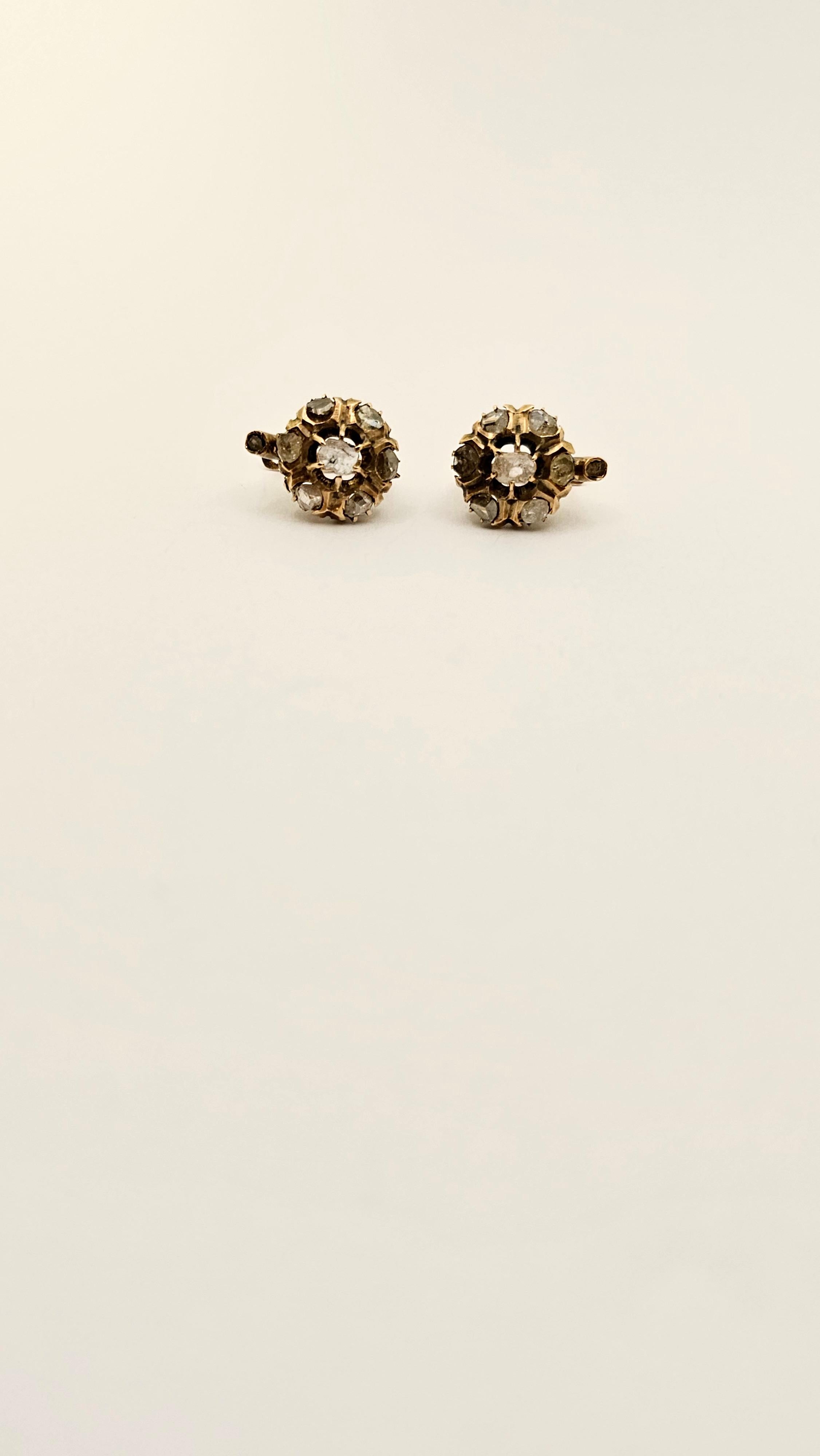 A pair of antique, Bourbon-style earrings in 9Kt rose gold.
These button-shaped earrings are 13 mm in diameter.
They are embellished with two central, rosette-cut Diamonds, measuring approximately 4x3 mm. Surrounding the center stones is a frame of