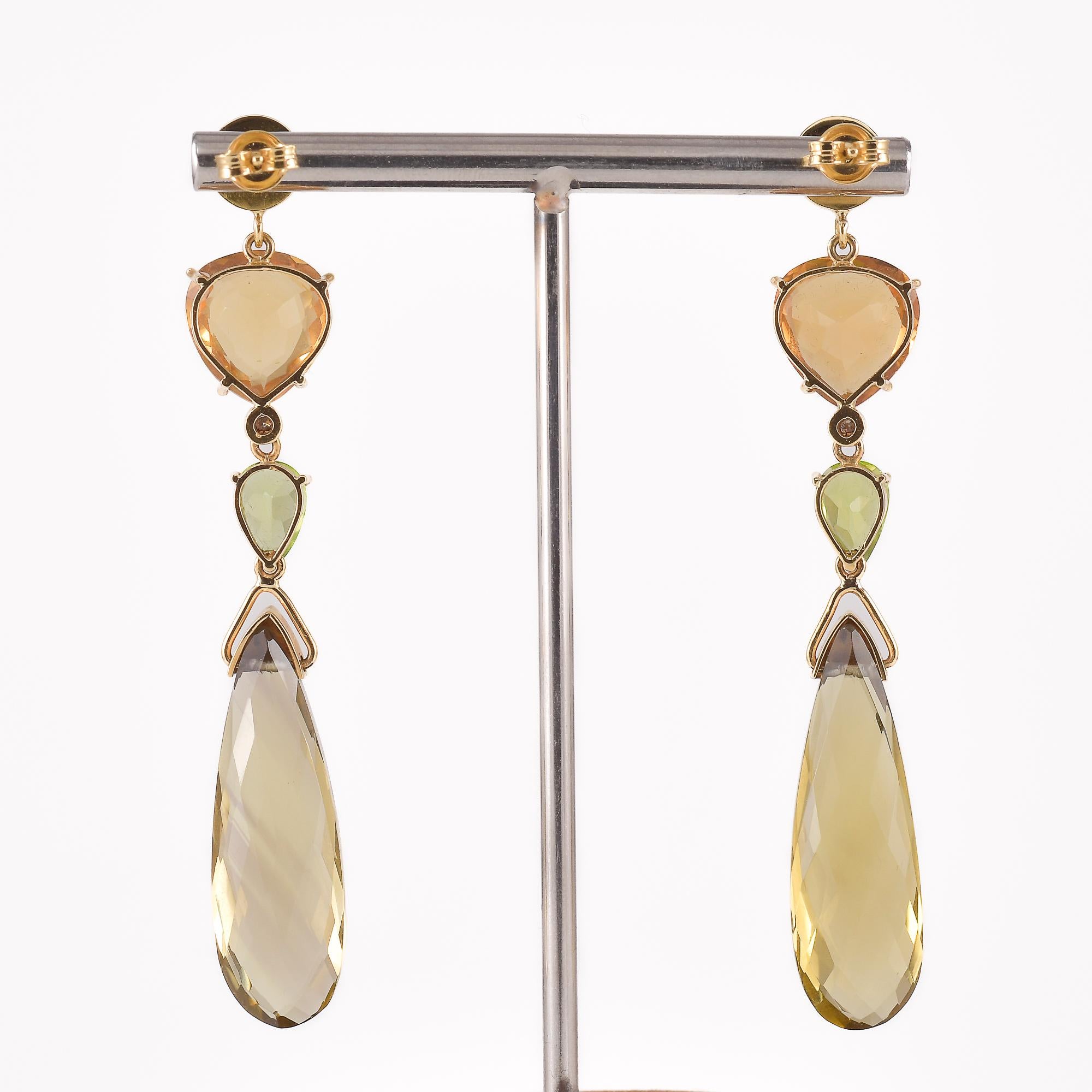 ANALYSE GEMMOLOGIQUE
Paire de boucles d'oreilles en or jaune 18k - 750/1000 poinçonnées - '750', chacune composée d'une ligne de quartz citrine, d'un diamant et d'un péridot, à laquelle est suspendue une briolette de quartz jaune-brun. Le poids
