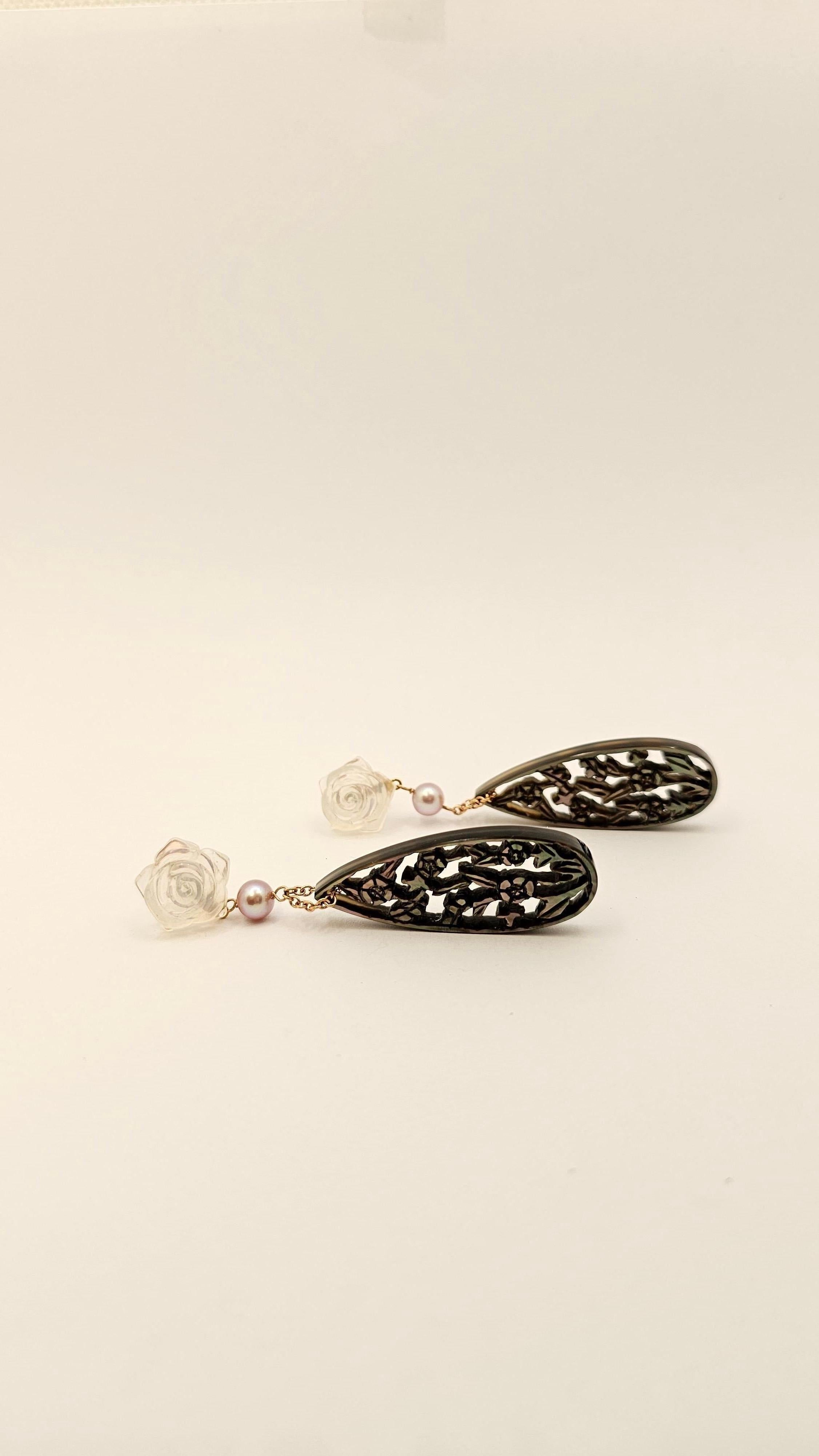A pair of pendant earrings made of 18 kt rose gold.
Featuring two hand-pierced dark gray mother-of-pearl drops and floral design measuring mm 40 x 15.
The part of the upper is composed of two rose-shaped engraved Crystals with a diameter of about