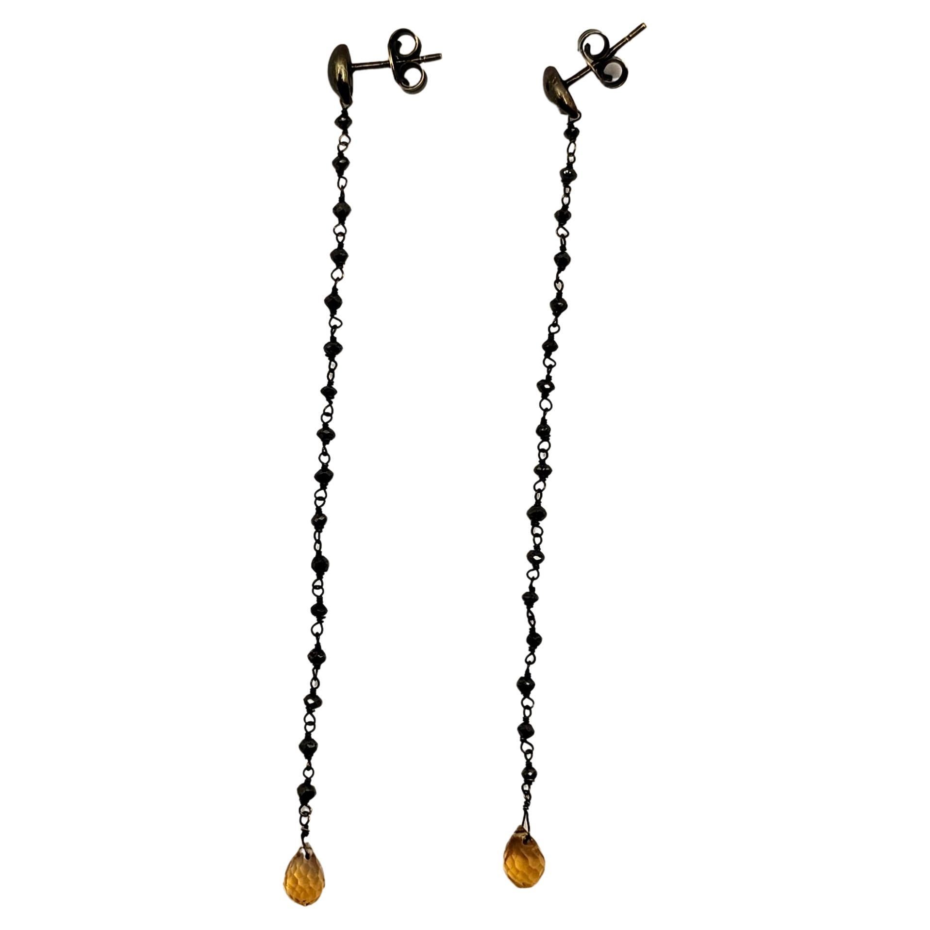 A pair of earrings made of 18 kt gold with a burnished finish.
The upper part of the clasp consists of pin and butterfly. From the clasp extends the dangling part of the earring made of gold and 16 black briolette-cut Diamonds per part.
The finial