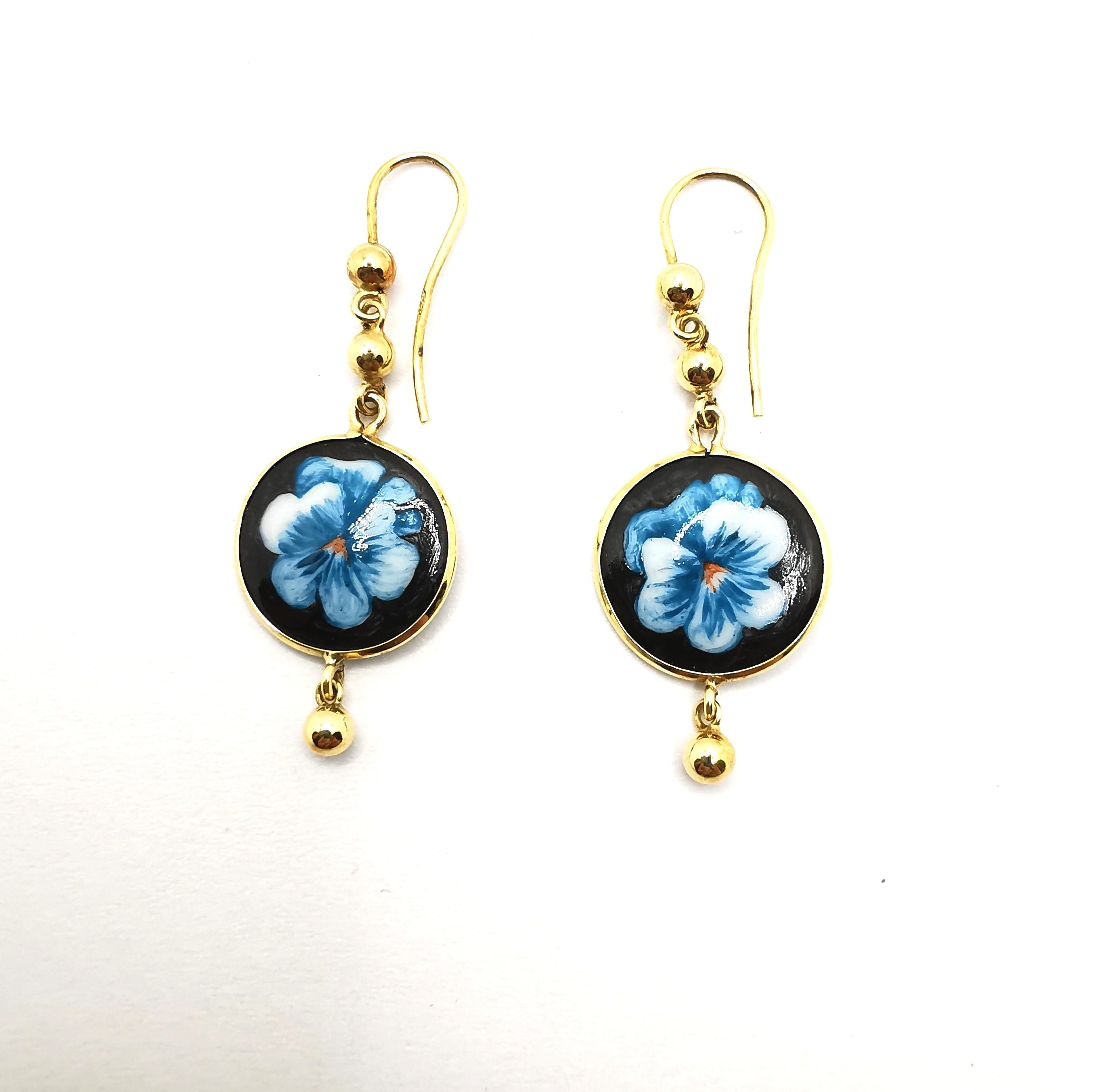 A cute pair of 18kt yellow gold and hand-painted porcelain dangle earrings.
The two inserts are painted in a floral pattern and bear the artist's signature on the back.
Each earring is embellished with three yellow gold spheres.
They are completely