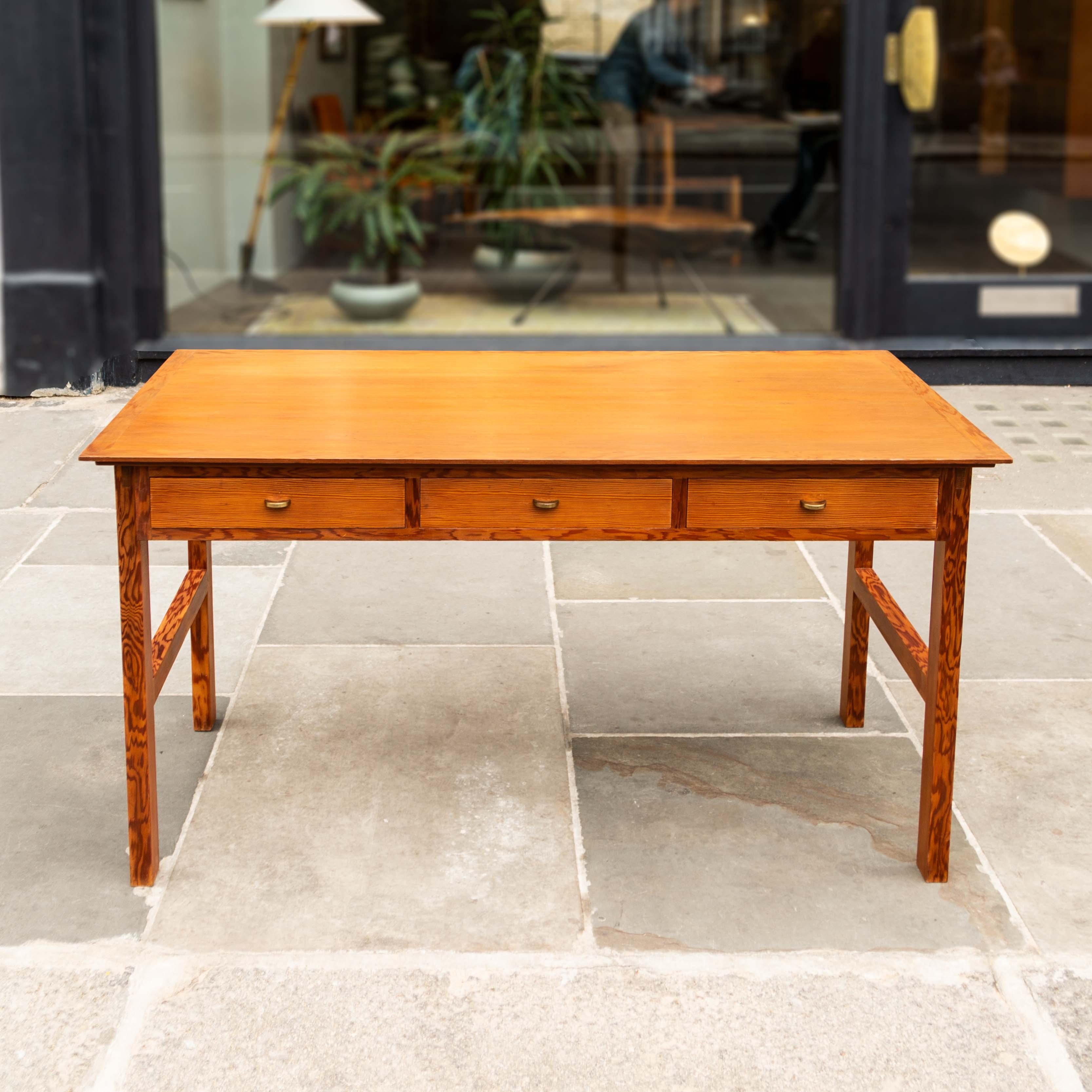 A well proportioned vintage desk made in Denmark, circa 1960.The main feature of this desk is the contrast between the plainer quarter-cut solid pine of the table top and drawer fronts, with the tiger-stripe crown-cut timber used in the rest of the